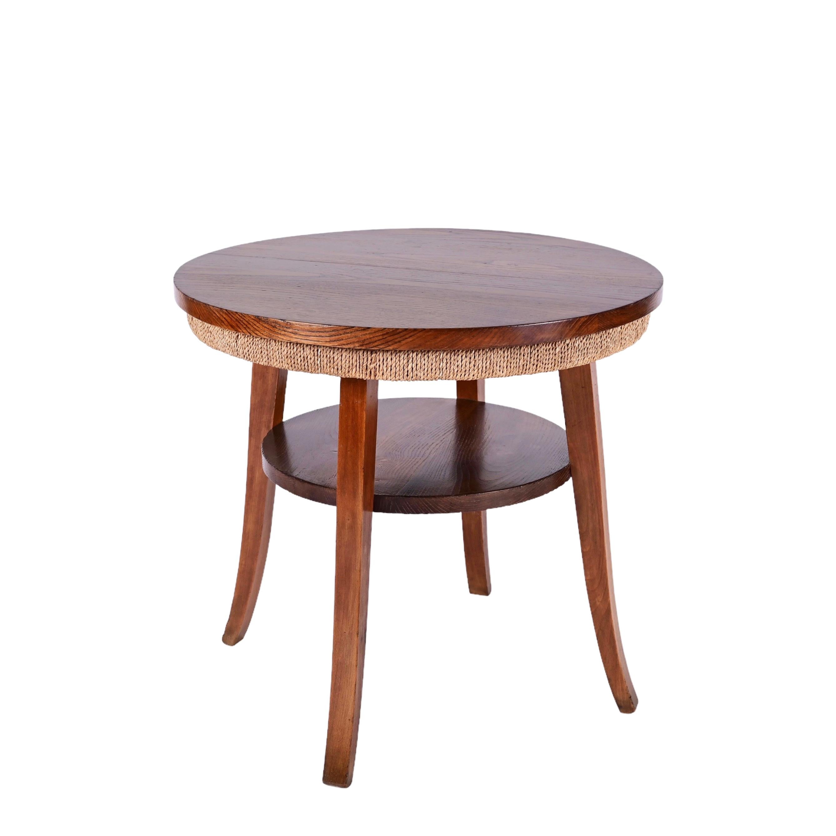 Midcentury two-tier round rope and chestnut wood coffee table. This incredible piece was produced in Italy during the 1950s, and it is attributed to Giuseppe Pagano Pogatschnig.

This item is a wonderful rope cocktail table with two shelves in