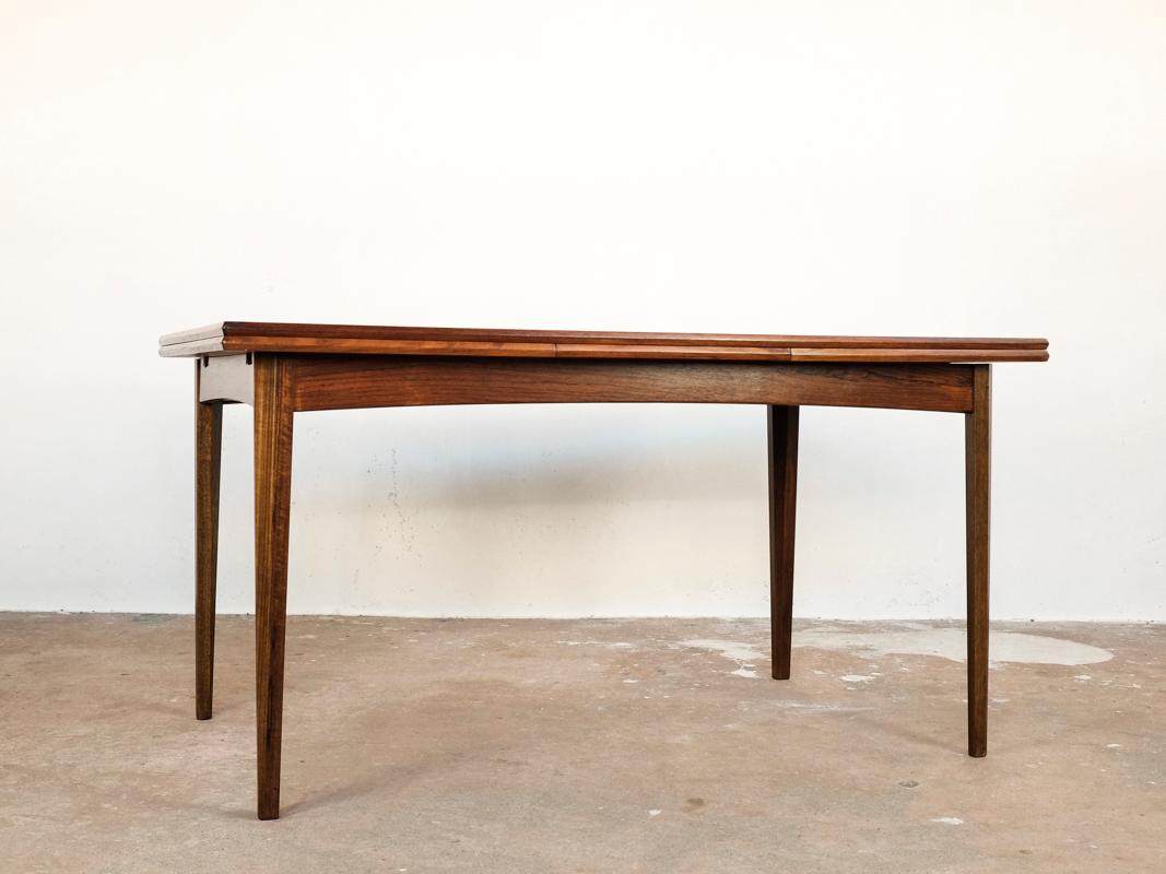 Midcentury table made in Denmark in the 1960s. The dining table is easily extendable on either one or both sides. It has nice drawings in the wood. It is made of rosewood and in very good condition. There are some minor dents in the