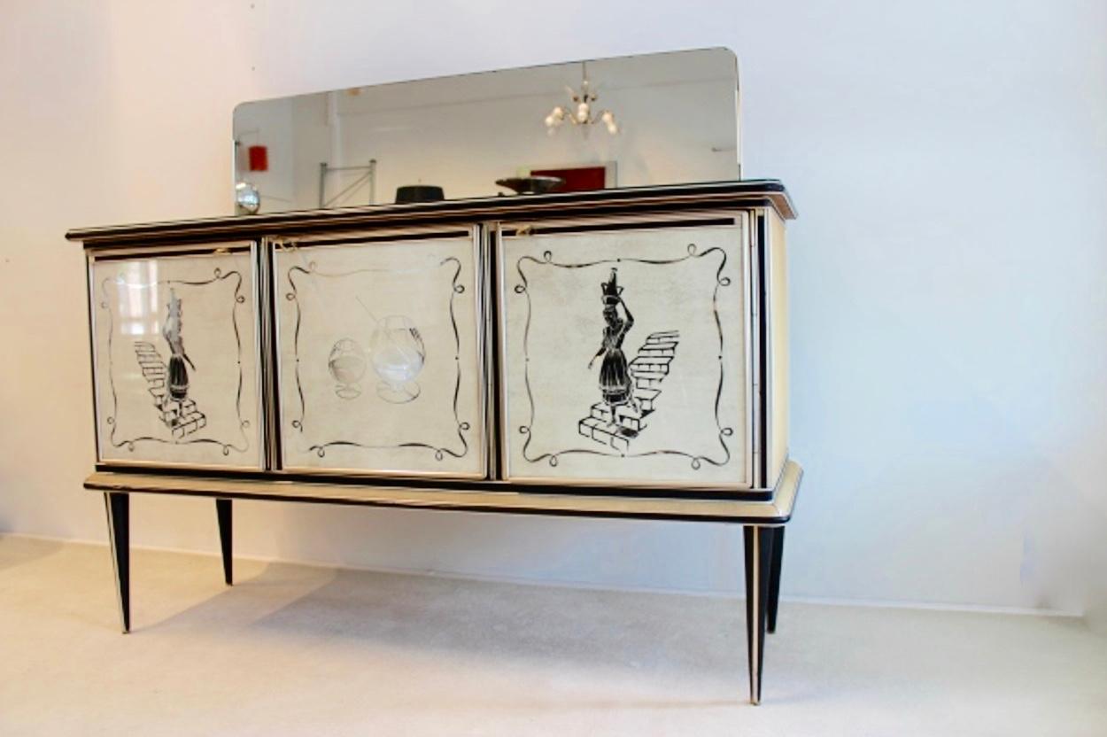 Rare and highly collectible bar credenza designed in Italy by Umberto Mascagni from Bologna. Early 1950s three doors cabinet created with reverse painted glass door fronts, two doors featuring a woman walking down the stairs, the central door