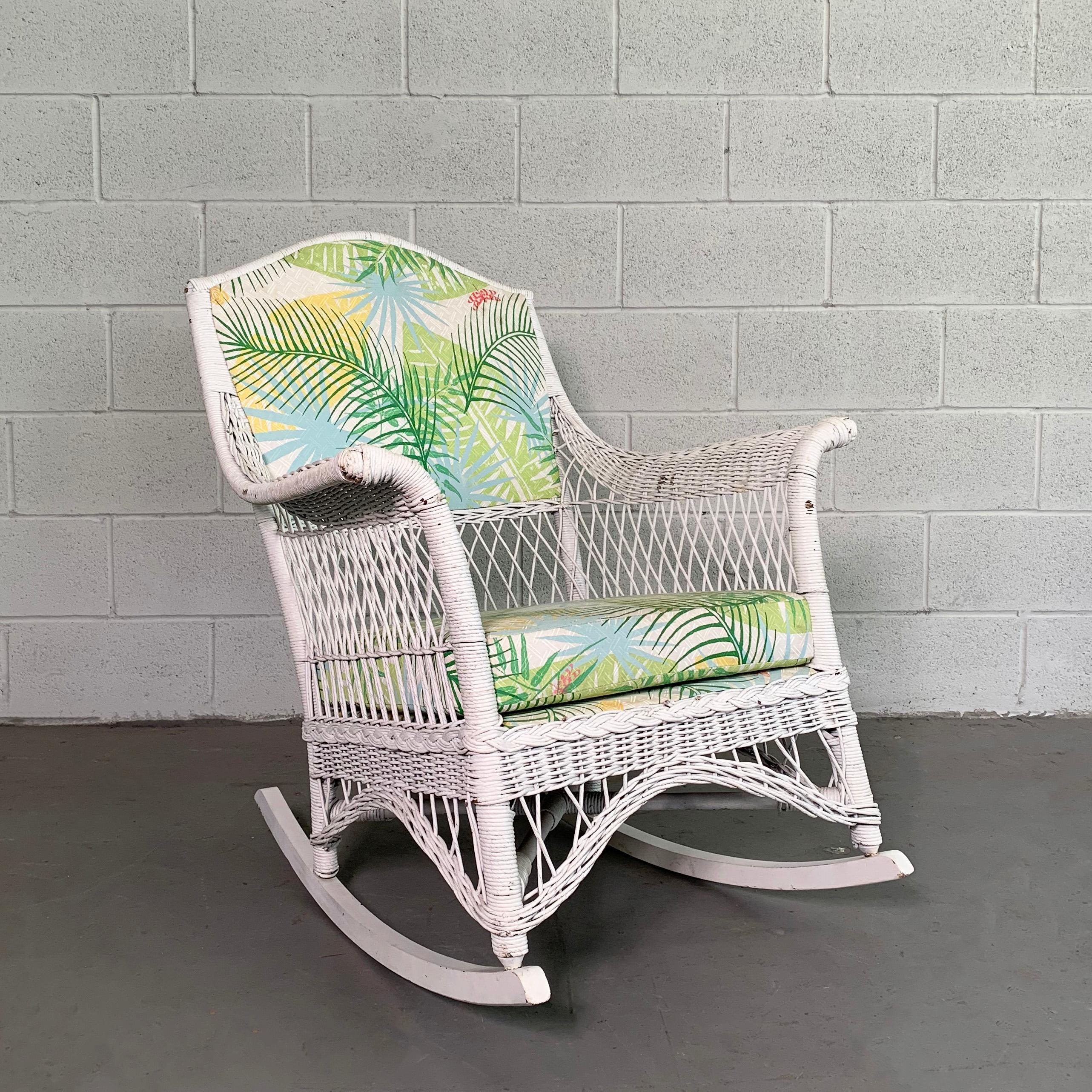 Cozy, midcentury, outdoor, garden/patio, rocking chair features a painted wicker frame with a newly upholstered back and seat in outdoor fabric.