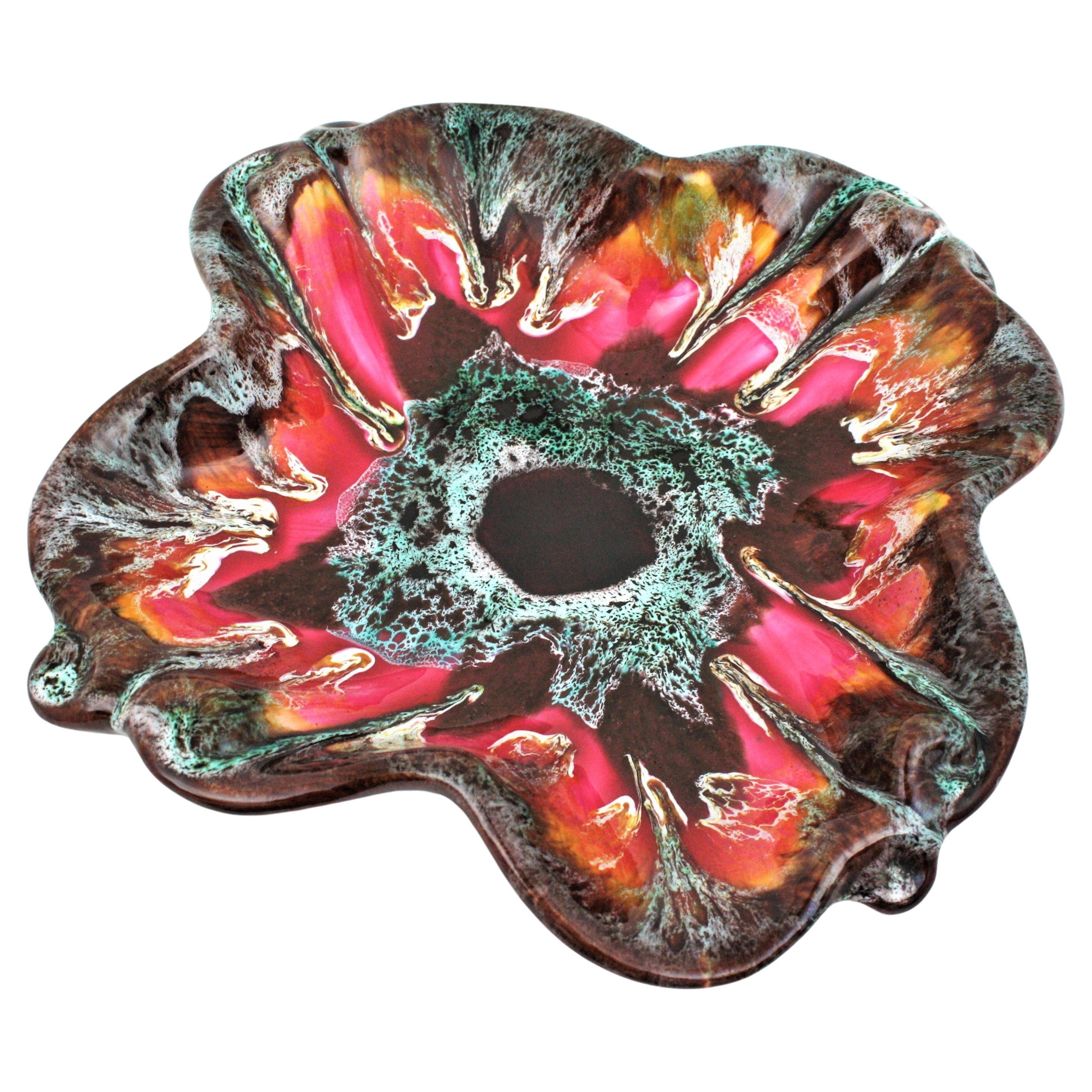 Mid-Century Modern multicolor glazed ceramic flower centerpiece bowl. Manufactured by Vallauris, France, 1950-1960.
Eye-catching and colorful flower shaped glazed ceramic platter or centerpiece bowl. Fat lava design in shades of red, orange, amber