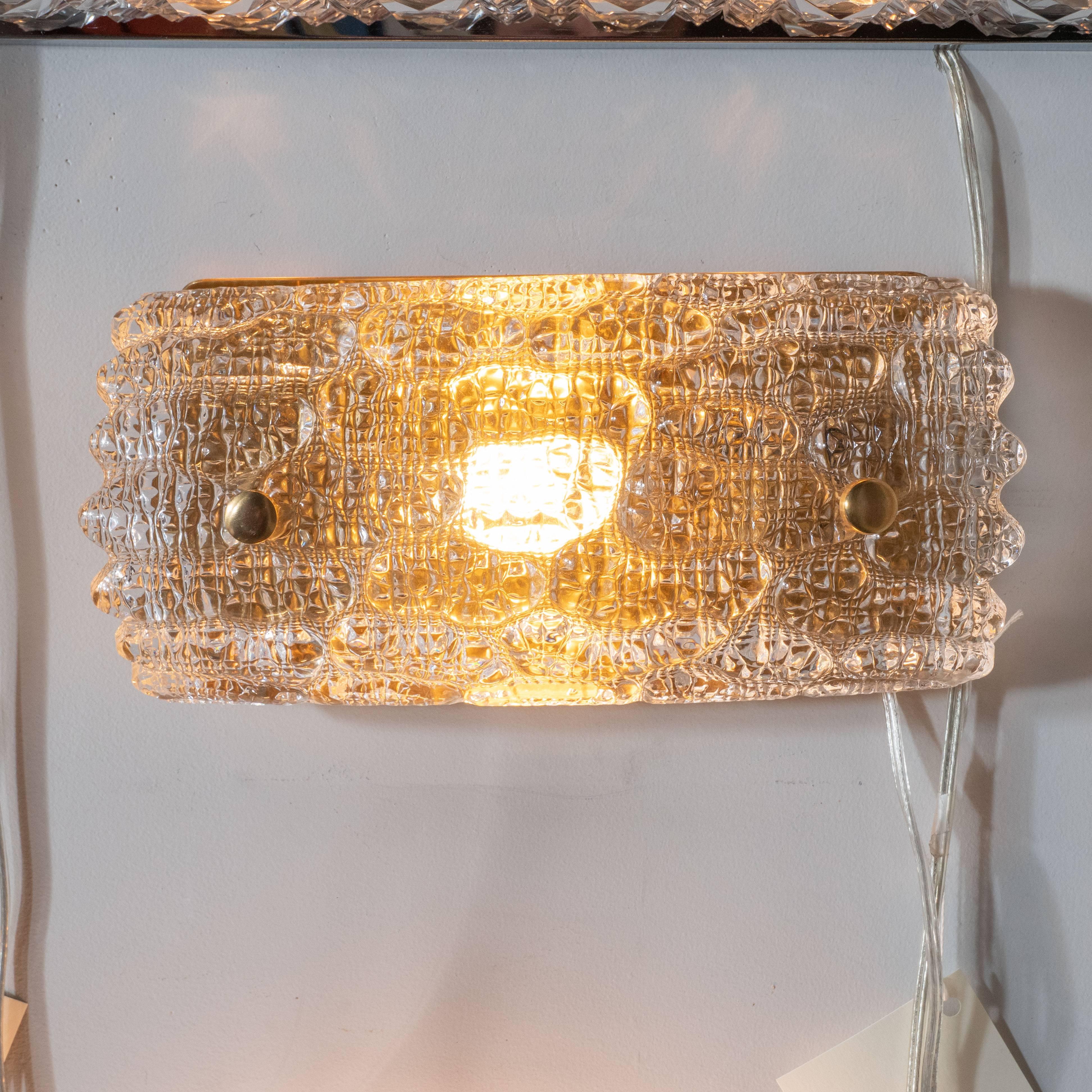 This refined vanity light was realized by the esteemed Mid-Century Modern designer Carl Fagerlund for Orrefors, circa 1960. It offers a vaulted body in handblown translucent glass of a subtle honey hue with a pattern resembling gauffraged crocodile.
