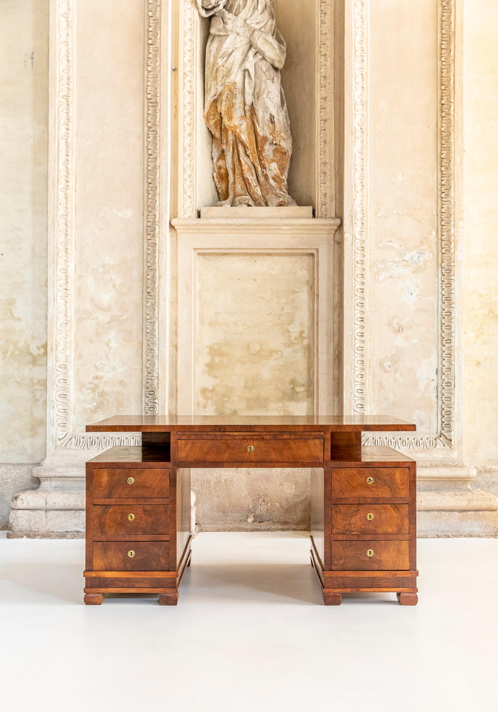 Elegant Italian design desk from 1930 with seven drawers in excellent condition. 
This desk is made entirely of veneered walnut, elegantly finished, as you can see from the details of the two legs, there are also the original keys of the drawers.