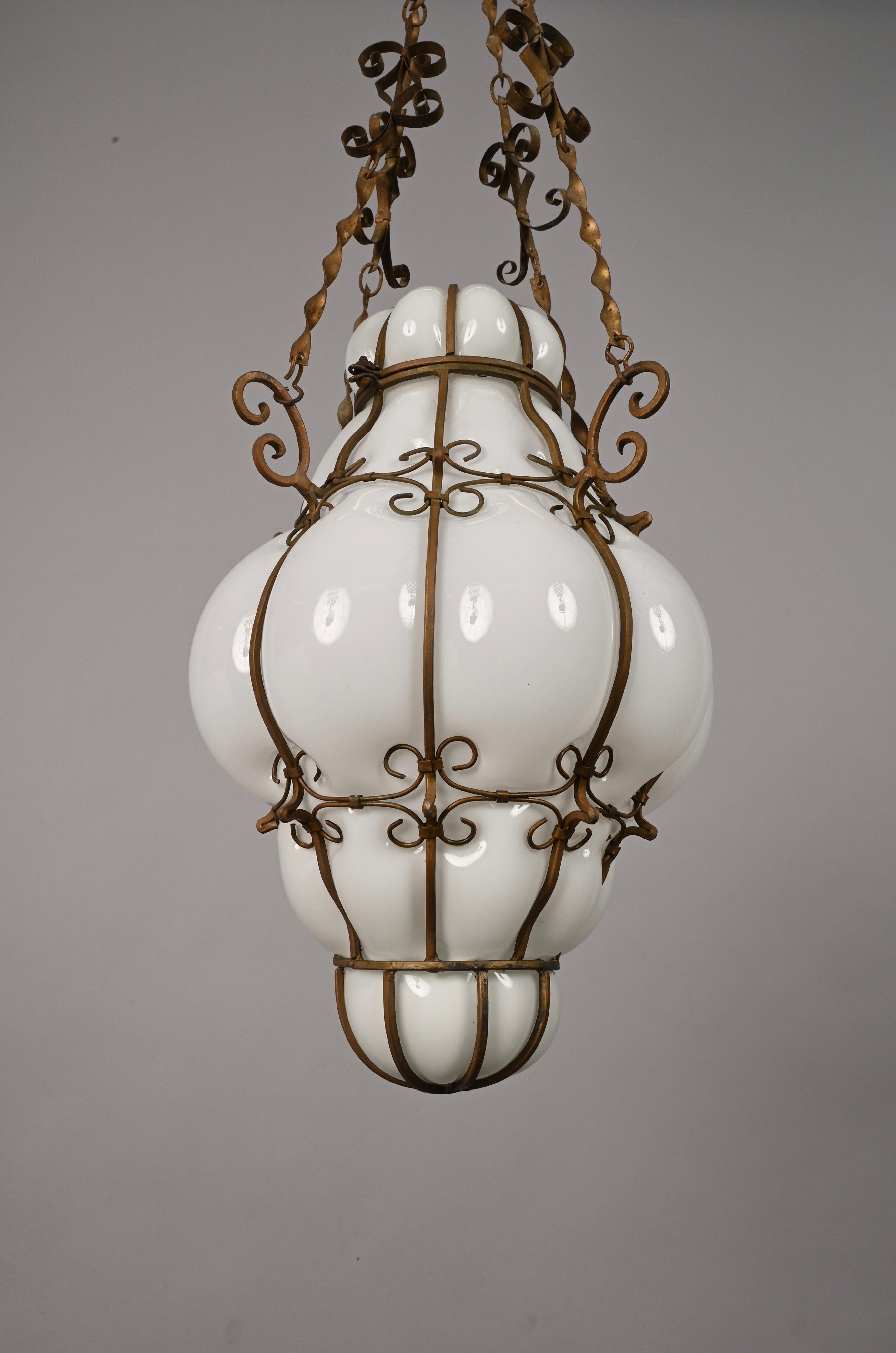 Incredible midcentury Venetian Murano white glass chandelier with an astonishing golden wrought iron frame. This outstanding piece was designed in Italy during the 1940s.

This chandelier is incredible because of the accuracy in the decoration of
