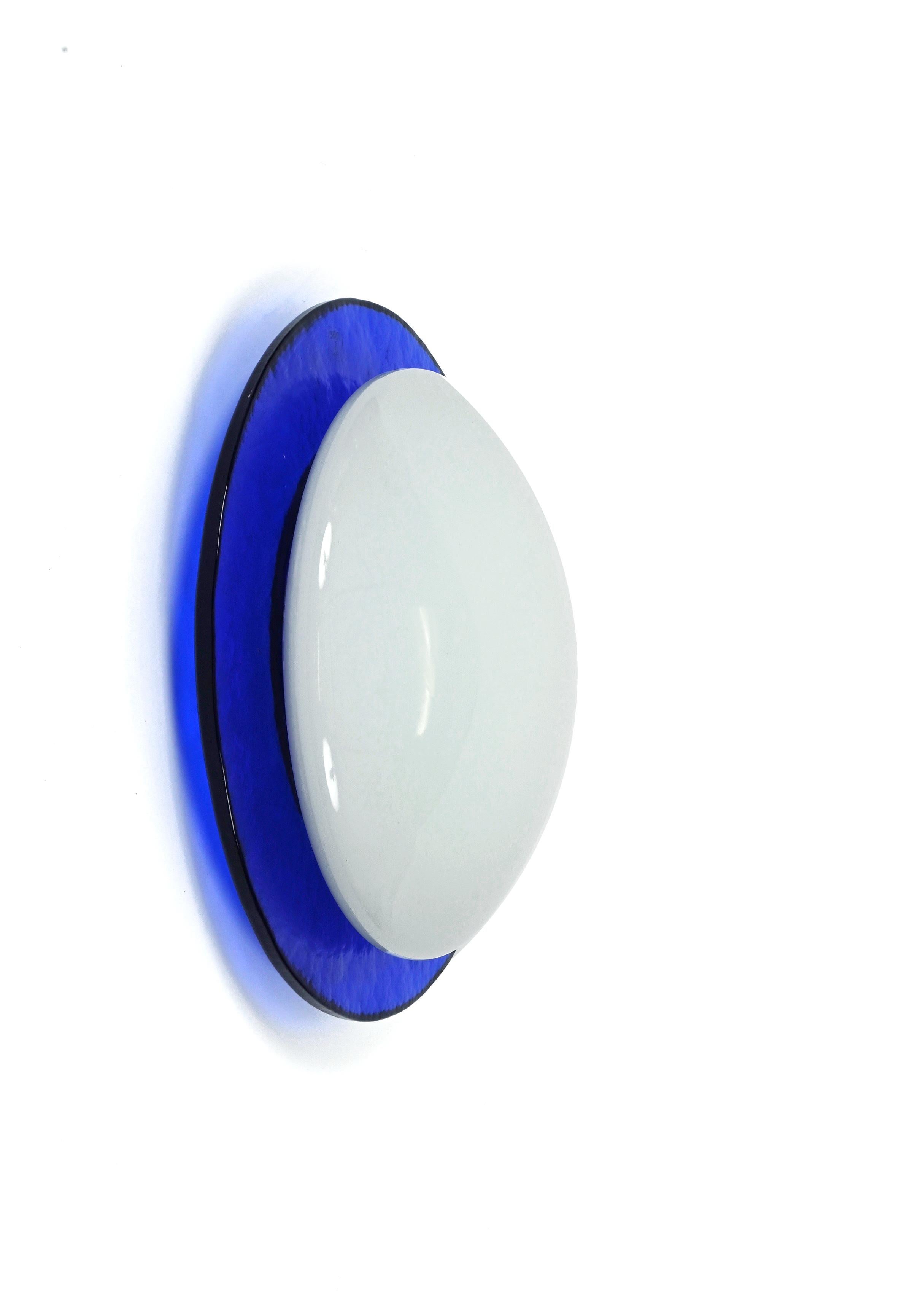 Fantastic mouth-blown round wall or ceiling sconce in embossed blue and white Murano glass. This magnificent light was designed in Italy during the 1980s.

This piece is wonderful because of the overlapping of a white Murano glass on the round