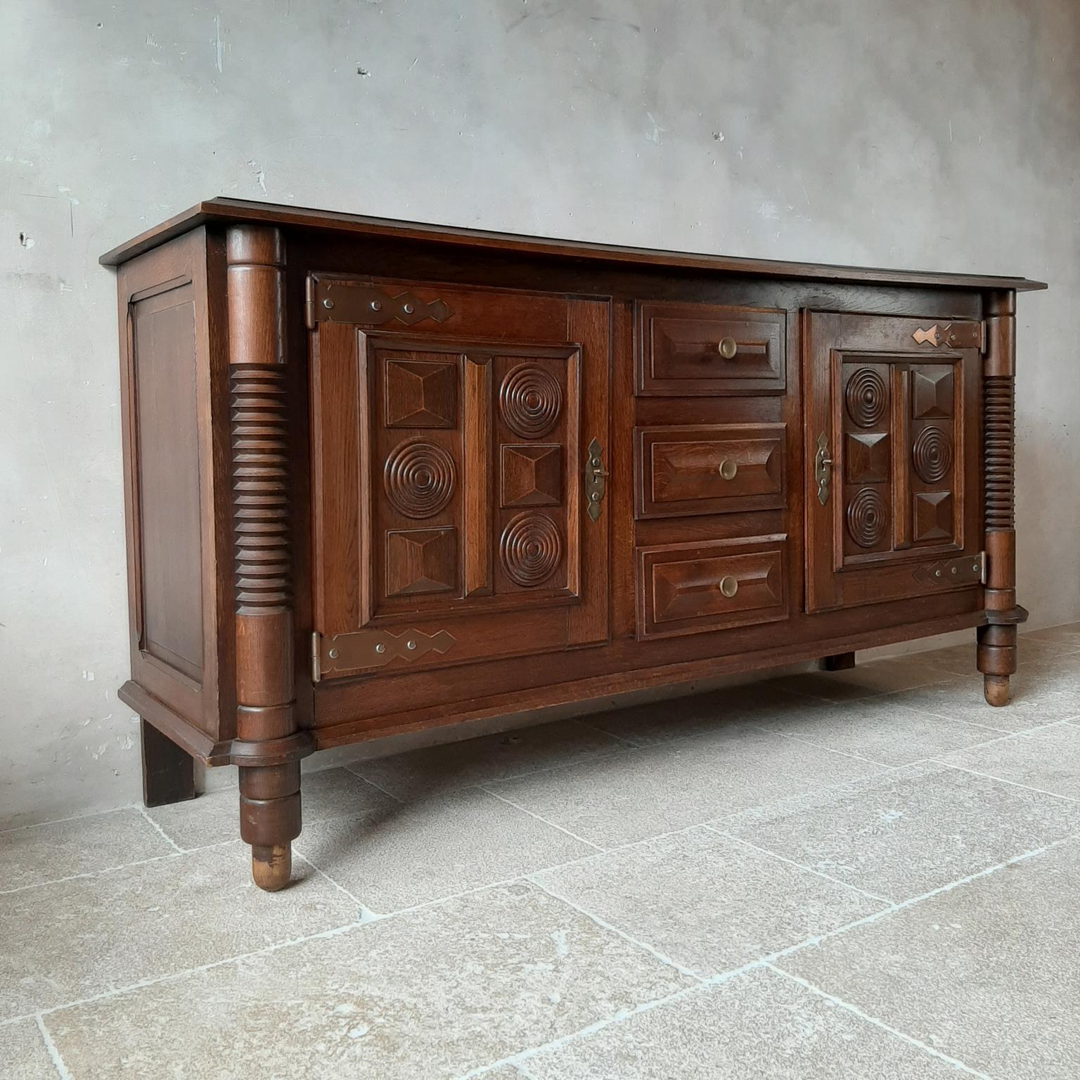 Midcentury vintage oak sideboard, credenza by Charles Dudouyt. This beautiful cabinet in Art Deco style shows off very fine craftsmanship. It features three drawers and two doors, decorated with typical Dudouyt geometrical shapes. This sideboard has