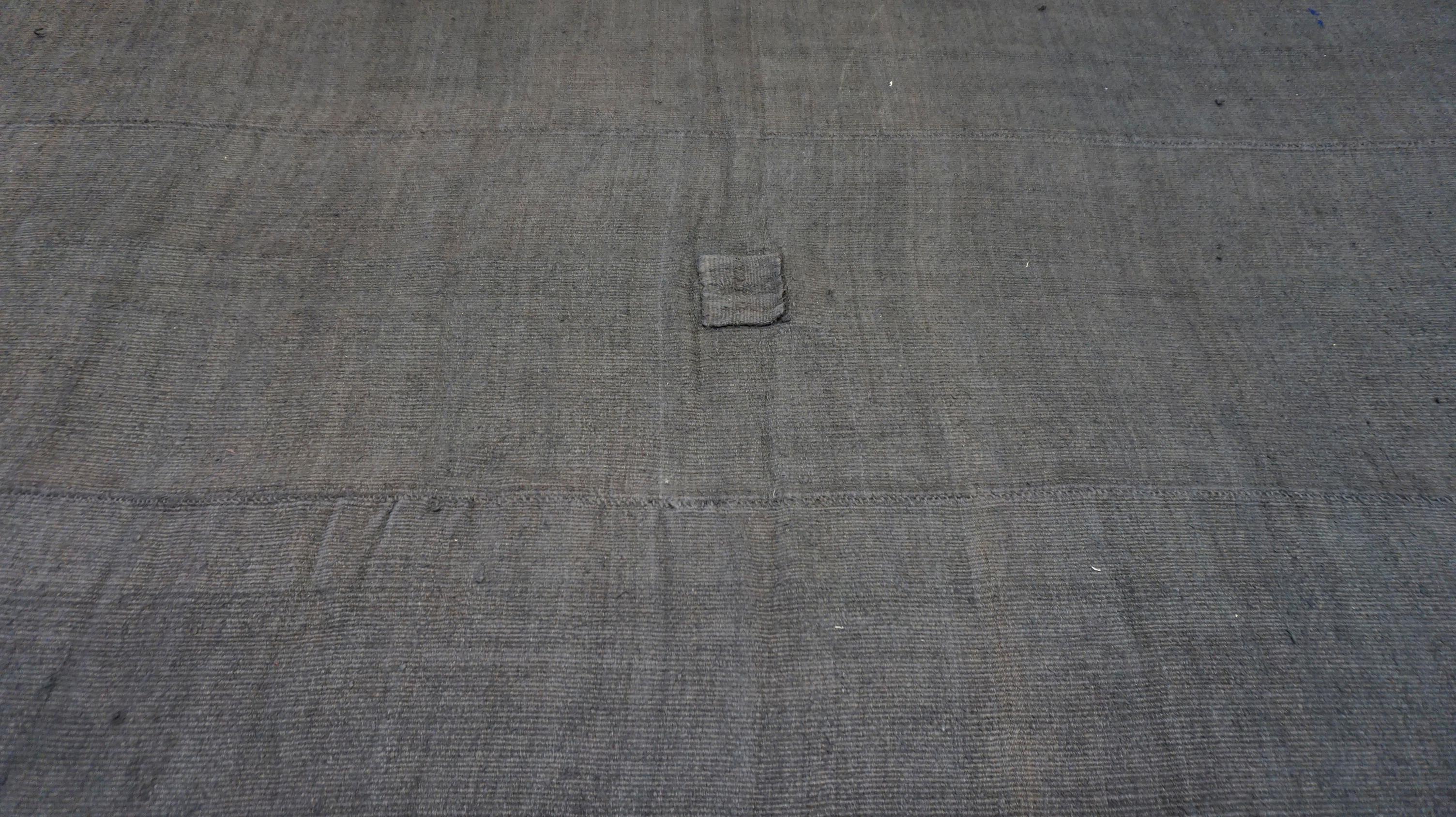 Dieser handgewebte Vintage-Teppich aus Hanf bietet mit seinem tiefen Anthrazit-Ton und seiner minimalistischen Ästhetik eine raffinierte Interpretation rustikaler Schlichtheit. Dieses handgefertigte Flachgewebe aus lokal bezogenen Hanfwollfasern ist