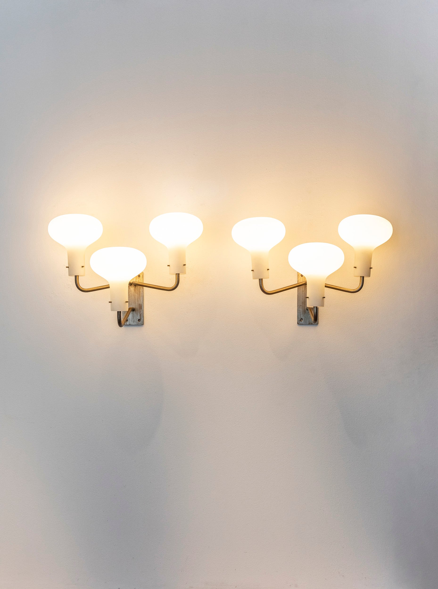 Ignazio Gardella for Azucena pair of wall lights or sconces model LP12 each with three opaque or frosted glass shades suspended from elegant patinated bronze finish brass arms and original backplates, Italy 1959.
Signed Azucena.

The wall lights