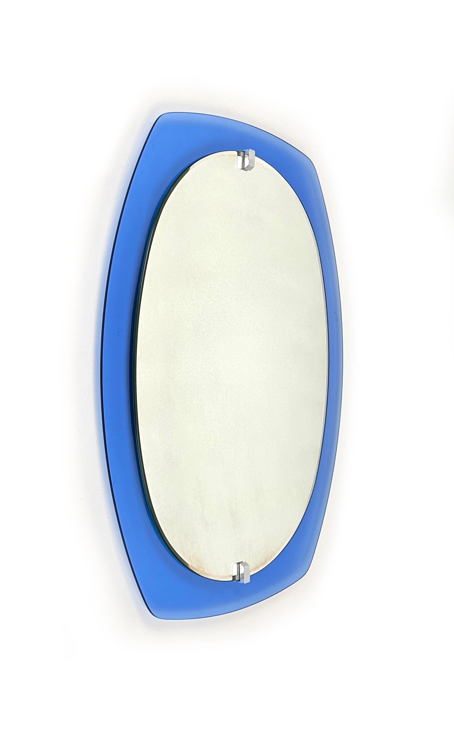 Midcentury Italian mirror, beveled looking glass mounted onto a blue glass background adhered with nickel fittings.

Made in Italy in the 1970s.

It comes with its original label signed 