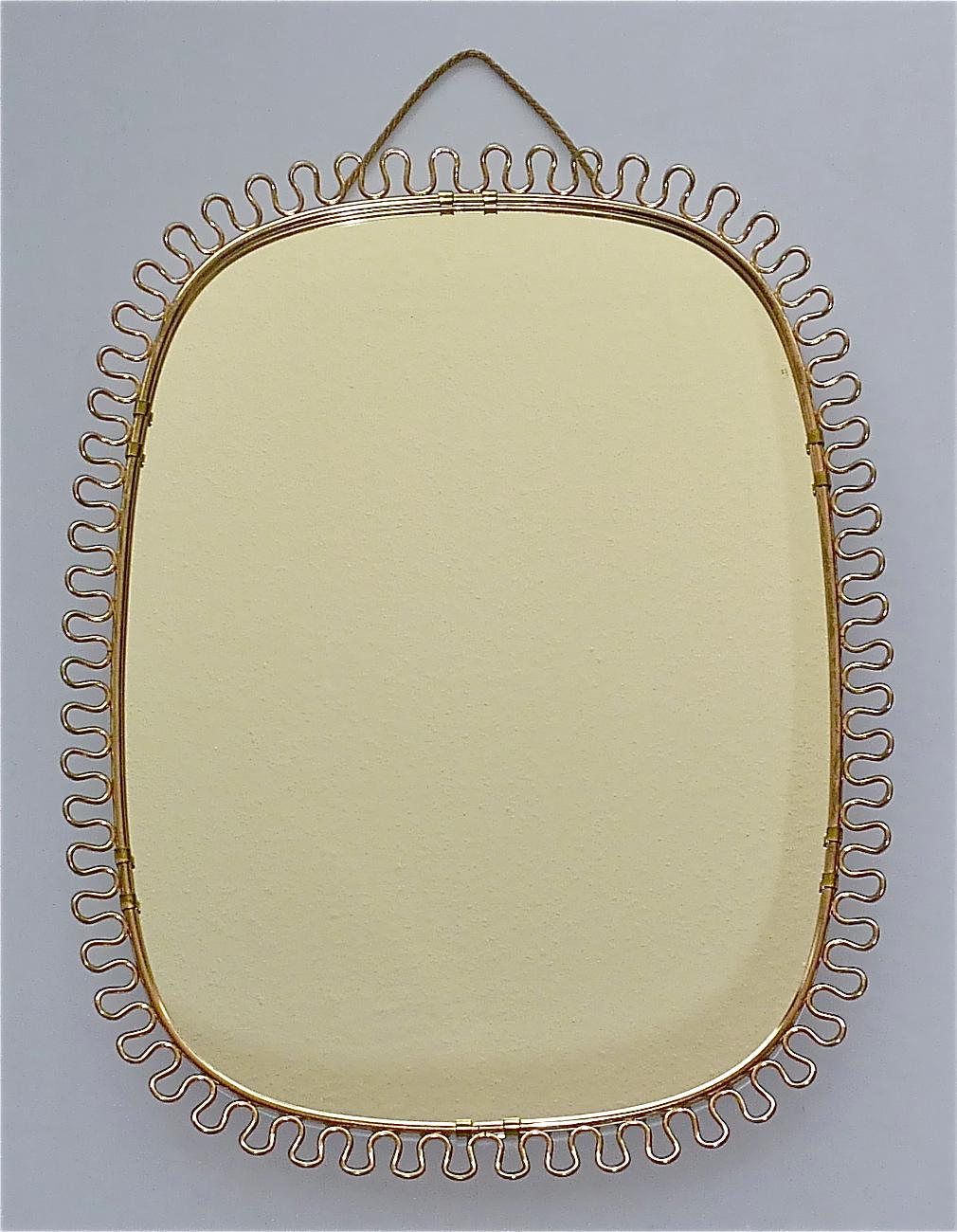 Sculptural and elegant mid-century wall mirror by Josef Frank Austria or Sweden for Svenskt Tenn, circa 1940s-1950s which is made of patinated brass metal, a beautiful brass loop-wire-decoration, original mirror glass, solid wood at the back and its