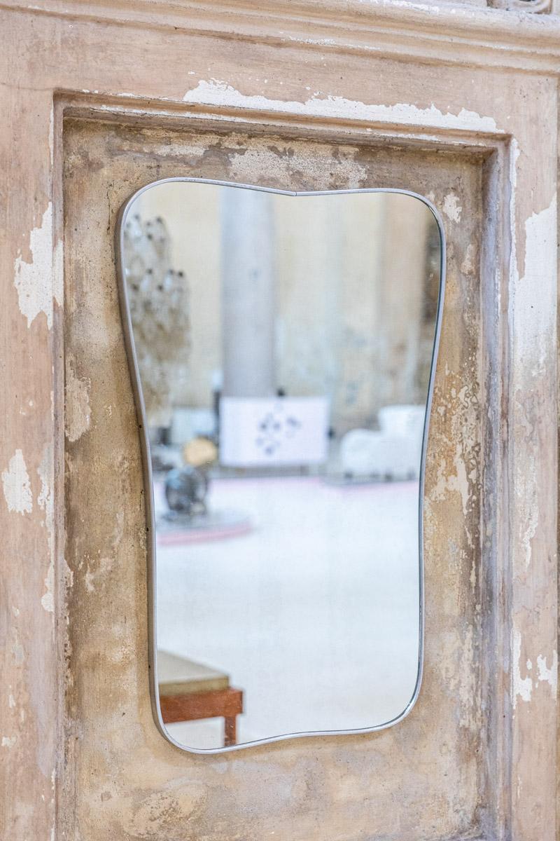 Élégant miroir mural, fabriqué en Italie dans les années 1950.
Cadre en aluminium patiné de forme sinueuse et miroir original, dans le style de Gio Ponti.