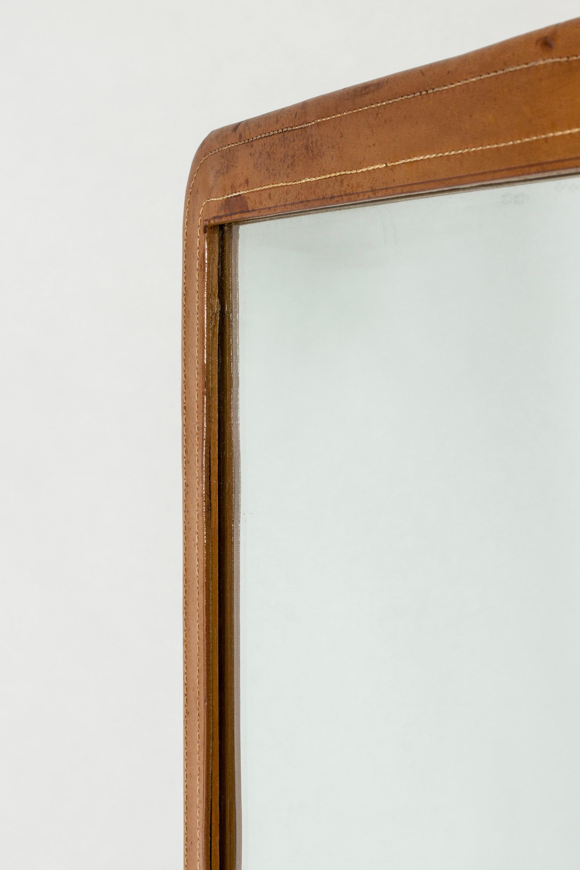 Cool vintage NK wall mirror, with frame dressed in cognac colored leather. Decorative white stitching.