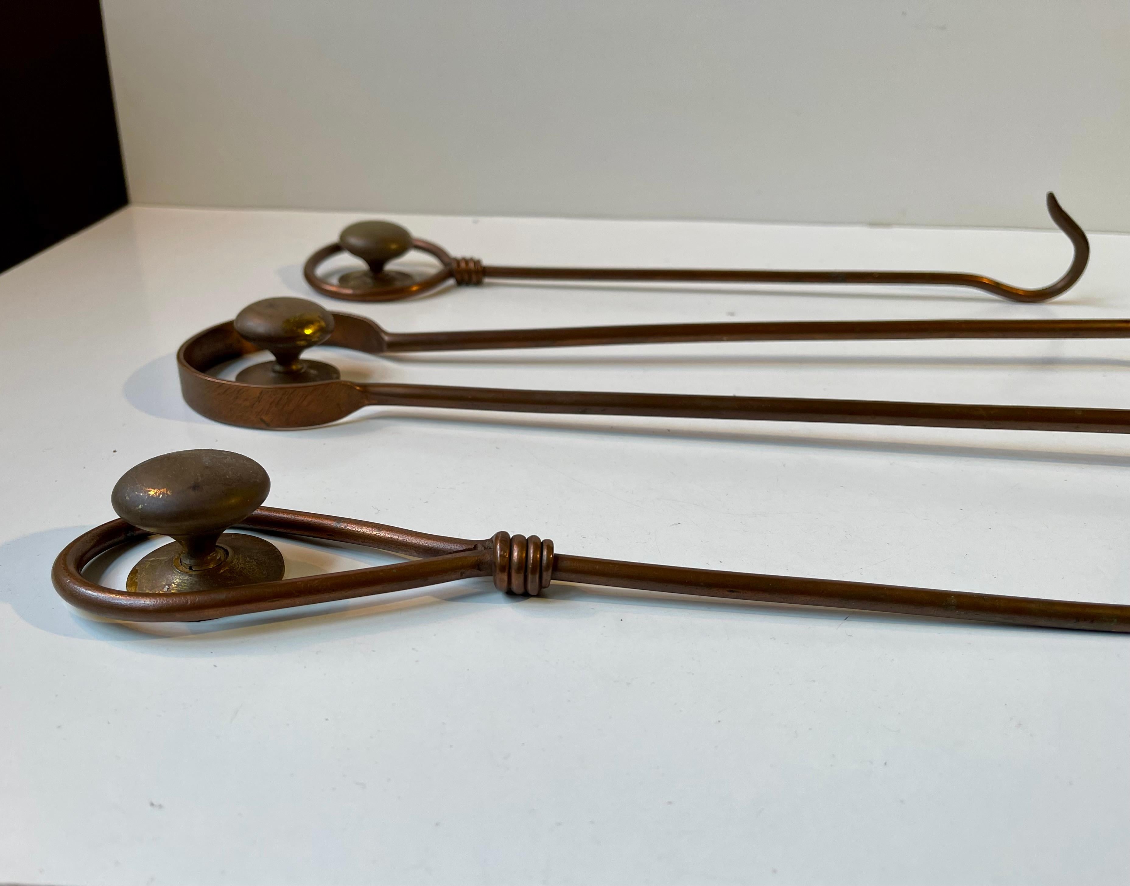 Ensemble mural d'outils de cheminée des années 1960, exécuté en cuivre partiellement torsadé. L'ensemble est livré avec 3 boutons en laiton massif patiné afin que vous puissiez conserver cet ensemble décoratif de votre mur à côté de votre cheminée.