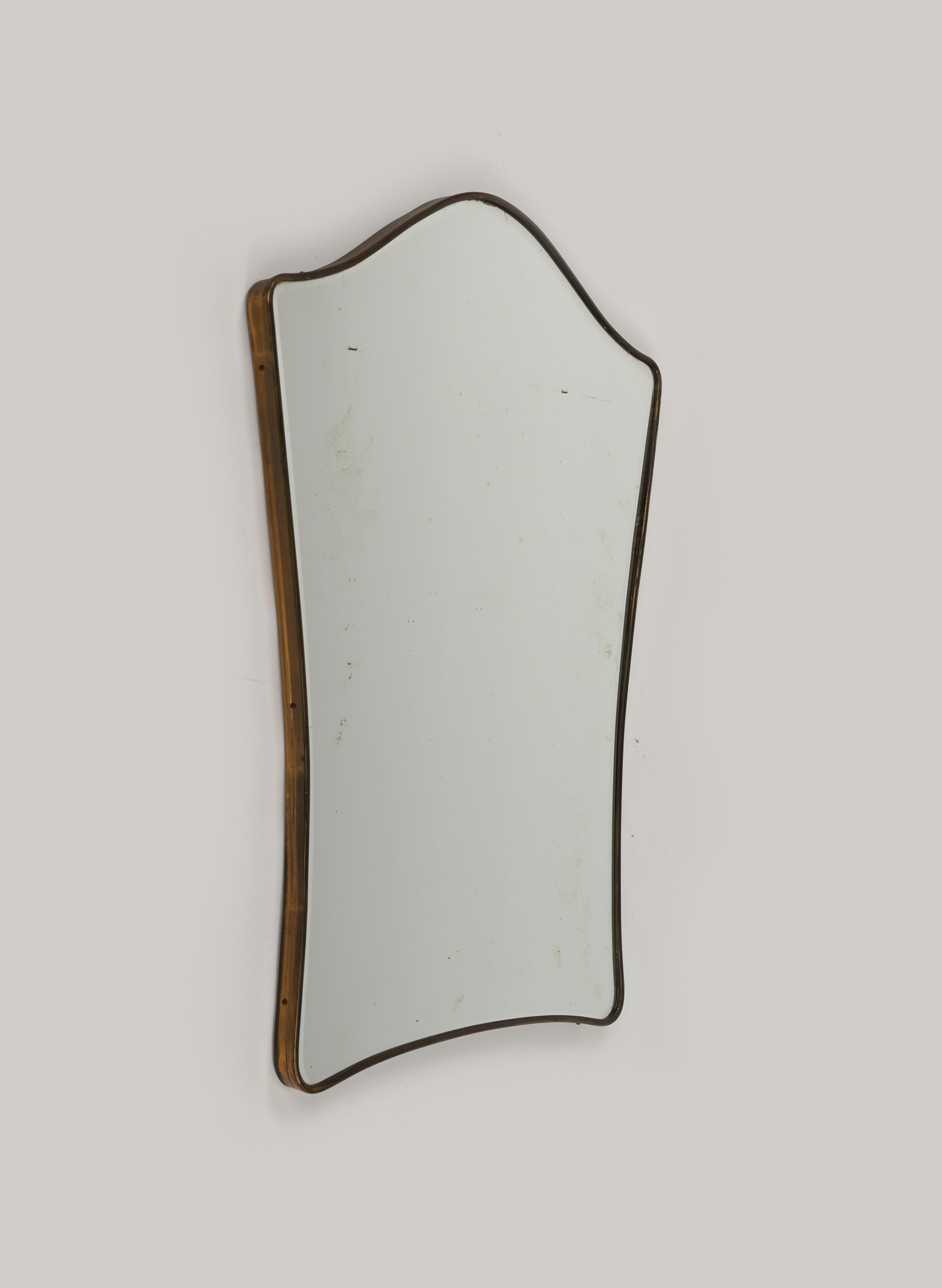 Beautiful Midcentury wall mirror in the shape of a shield framed with brass in the style of the Italian designer Gio Ponti.

Made in Italy in the 1950s.

The mirror is very well-made, original of the period, shows signs of discolouration.