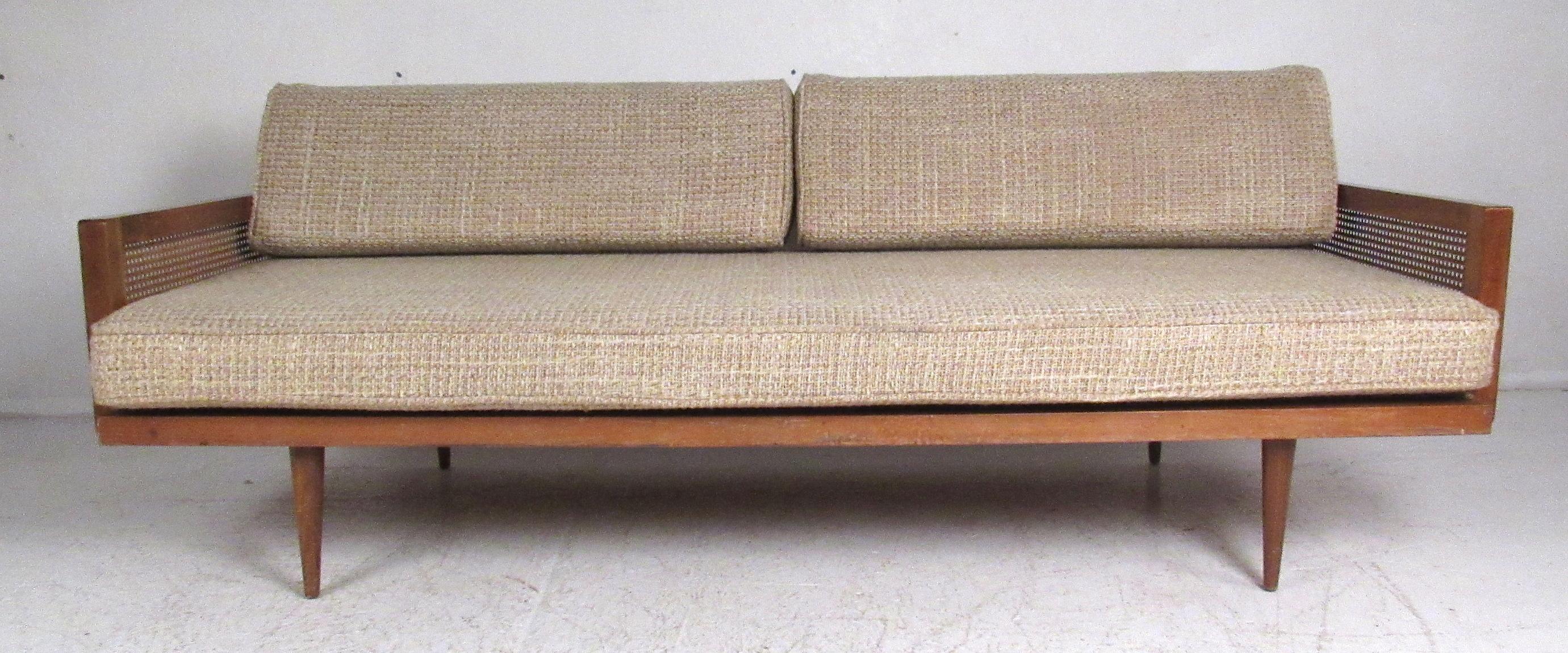 Vintage midcentury walnut frame sofa with cane sides and tapered legs. Nicely proportioned, with the long tapered legs creating an elegant airy quality, typical of midcentury design. Please confirm item location (NY or NJ) with dealer.
 