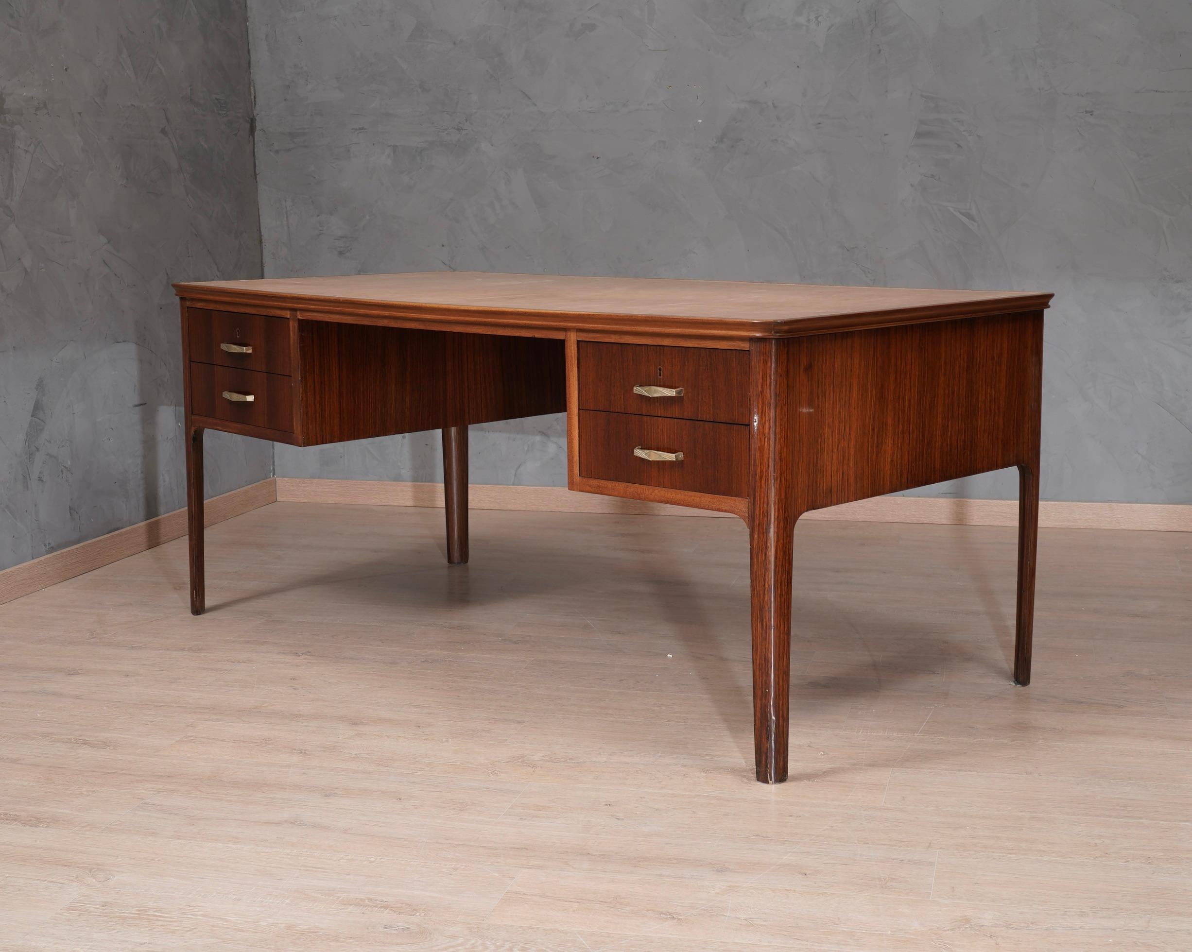 Elegante escritorio italiano de cuero y madera de nogal, diseño clásico y muy lineal para un escritorio de mediados del siglo pasado.

La parte superior del escritorio está toda cubierta de cuero marrón claro, con un borde de madera que recorre el