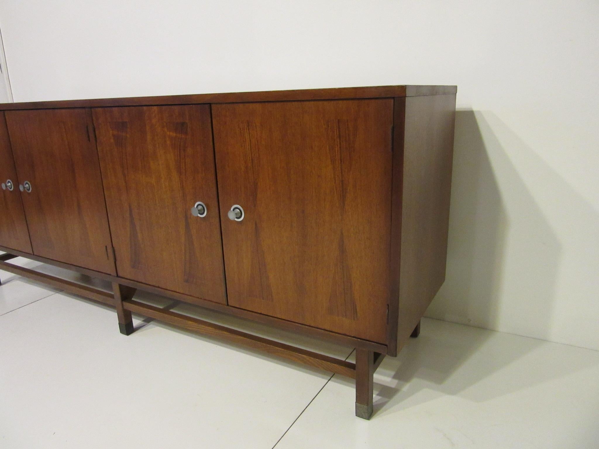 A well grained walnut credenza / server buffet with inlay rosewood details to the front and top, two doors to one side containing an adjustable shelve and three drawers to the other, one having dividers for smaller items. Turned stainless pulls to