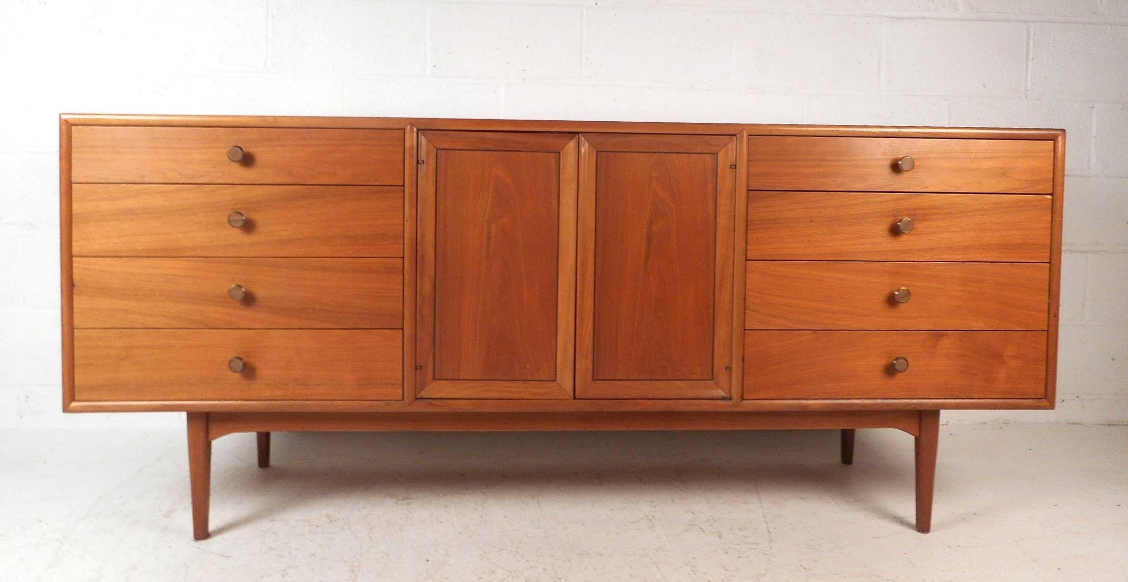 Beautiful vintage modern sideboard by Drexel with eleven hefty drawers for storage. This stunning case piece has unique circular metal pulls with wood fronts. Two cabinet doors with a spring mechanism hide three large drawers in the centre. A