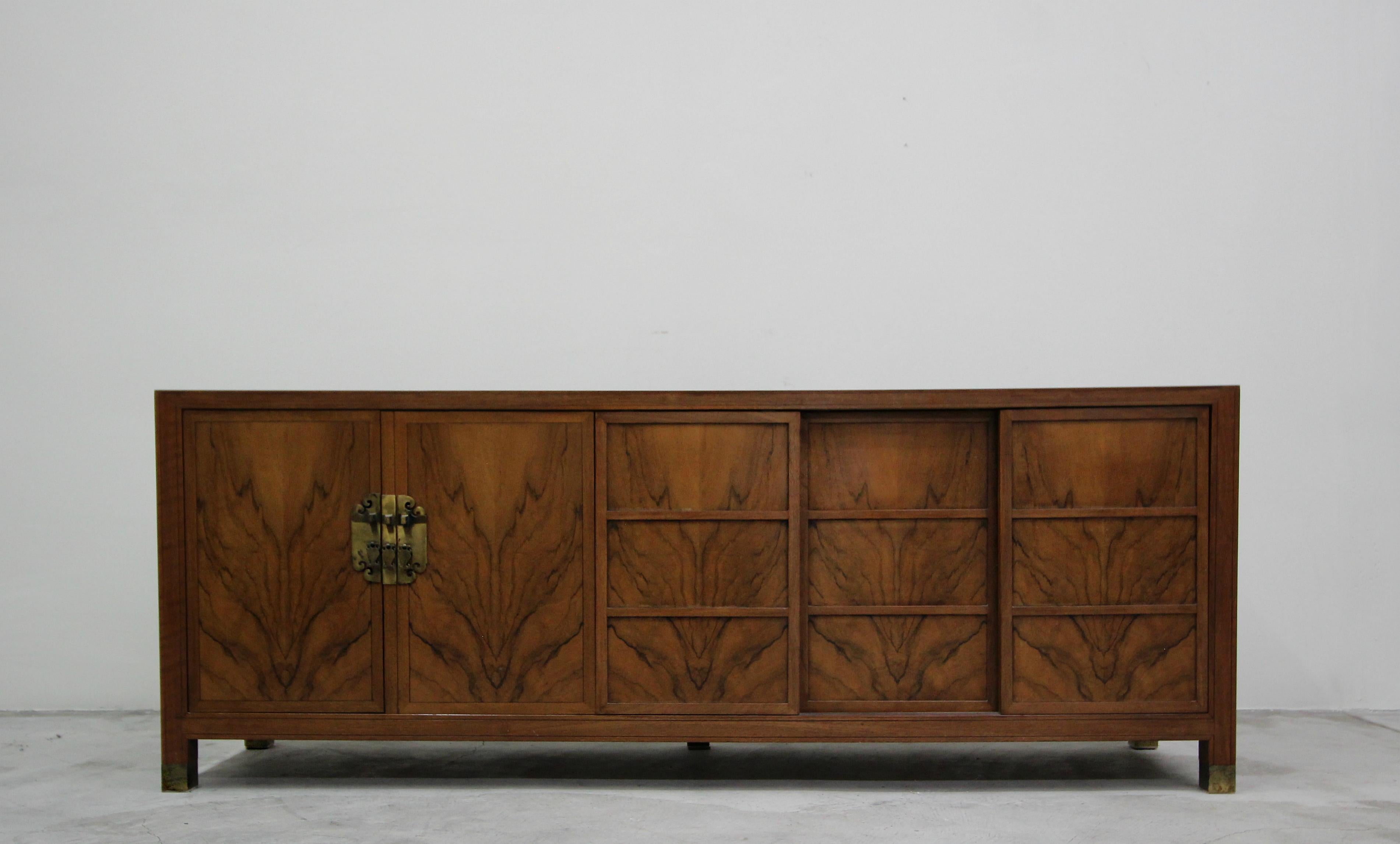Beautiful midcentury walnut credenza. When it comes to amazing grain, this beauty takes the cake. Designed by Frank Van Steenberg for the Baker Far East Collection, the brass escutcheon details and shoji screen style doors give it that Asian flair.
