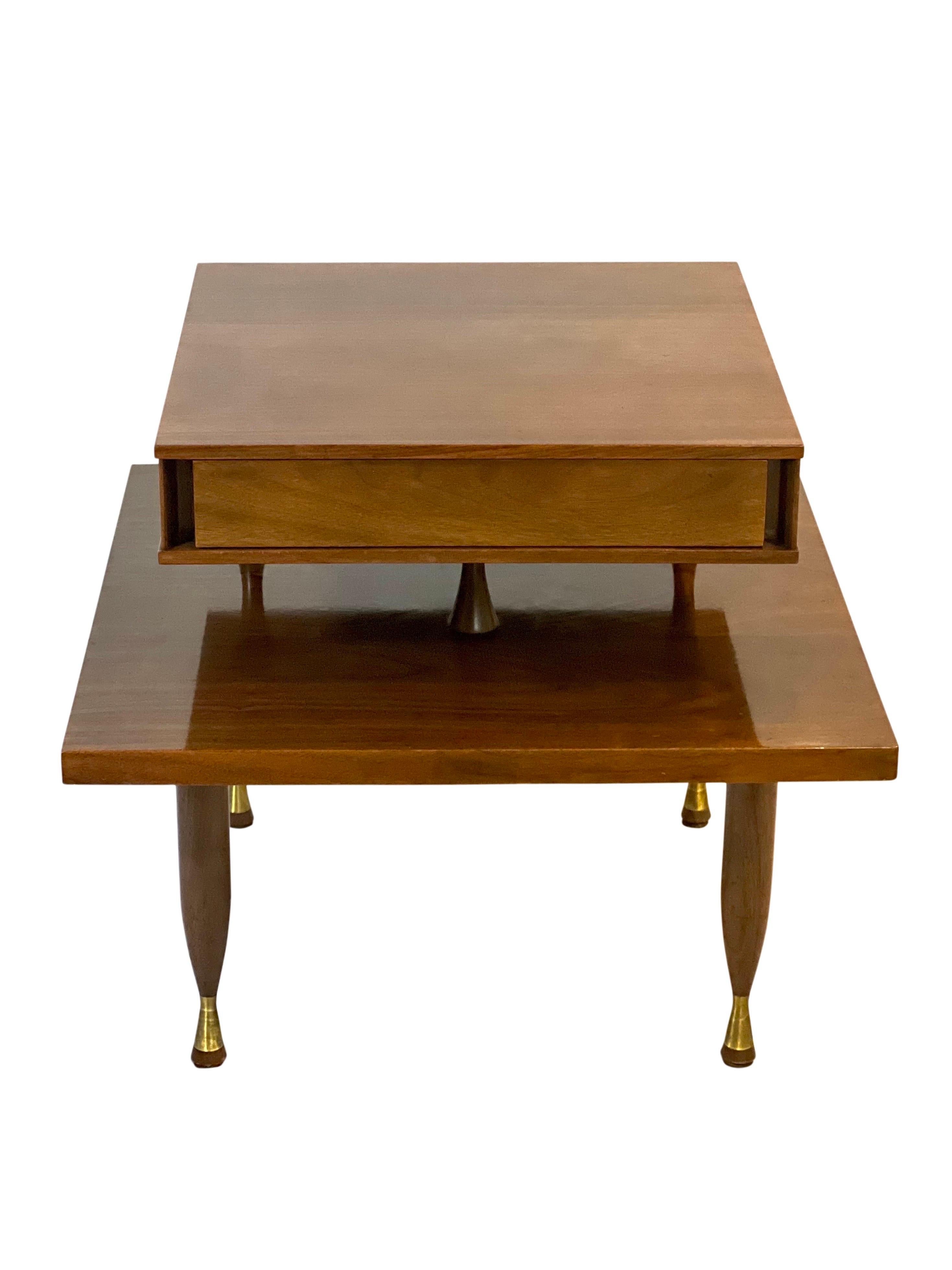 Midcentury walnut floating two tier side table in the manner of John Widdicomb. 

A refined table featuring a floating top tier with a single, minimalistic drawer. Elegant detail throughout including three hourglass shaped supports and uniquely