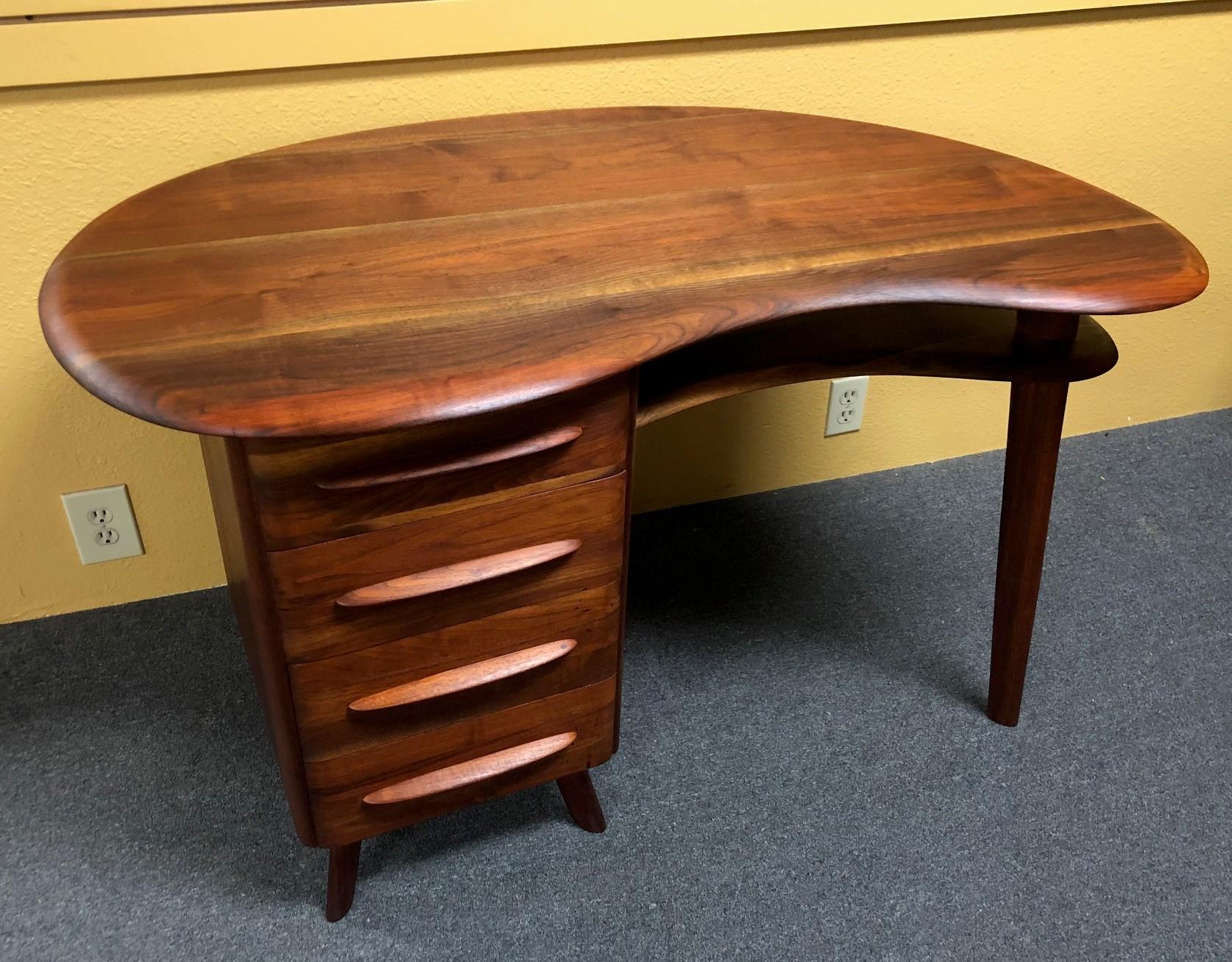 Mid-Century Modern kidney shaped writing desk by Carl Bissman for Bissman Furniture Company, circa 1950s. The desk features a freeform surface with three drawers and solid walnut construction. Bissman Furniture of Springfield, Missouri only