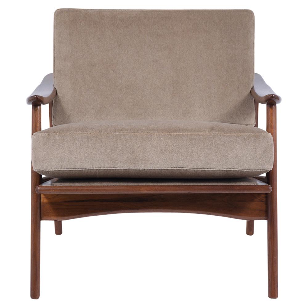 A 1960s Danish Modern Lounge Chair handcrafted out of walnut wood with a newly stained lacquered finish and are professionally restored. This armchair feature sculpted slatted backrests, paddle-shaped armrests, and has been newly upholstered in