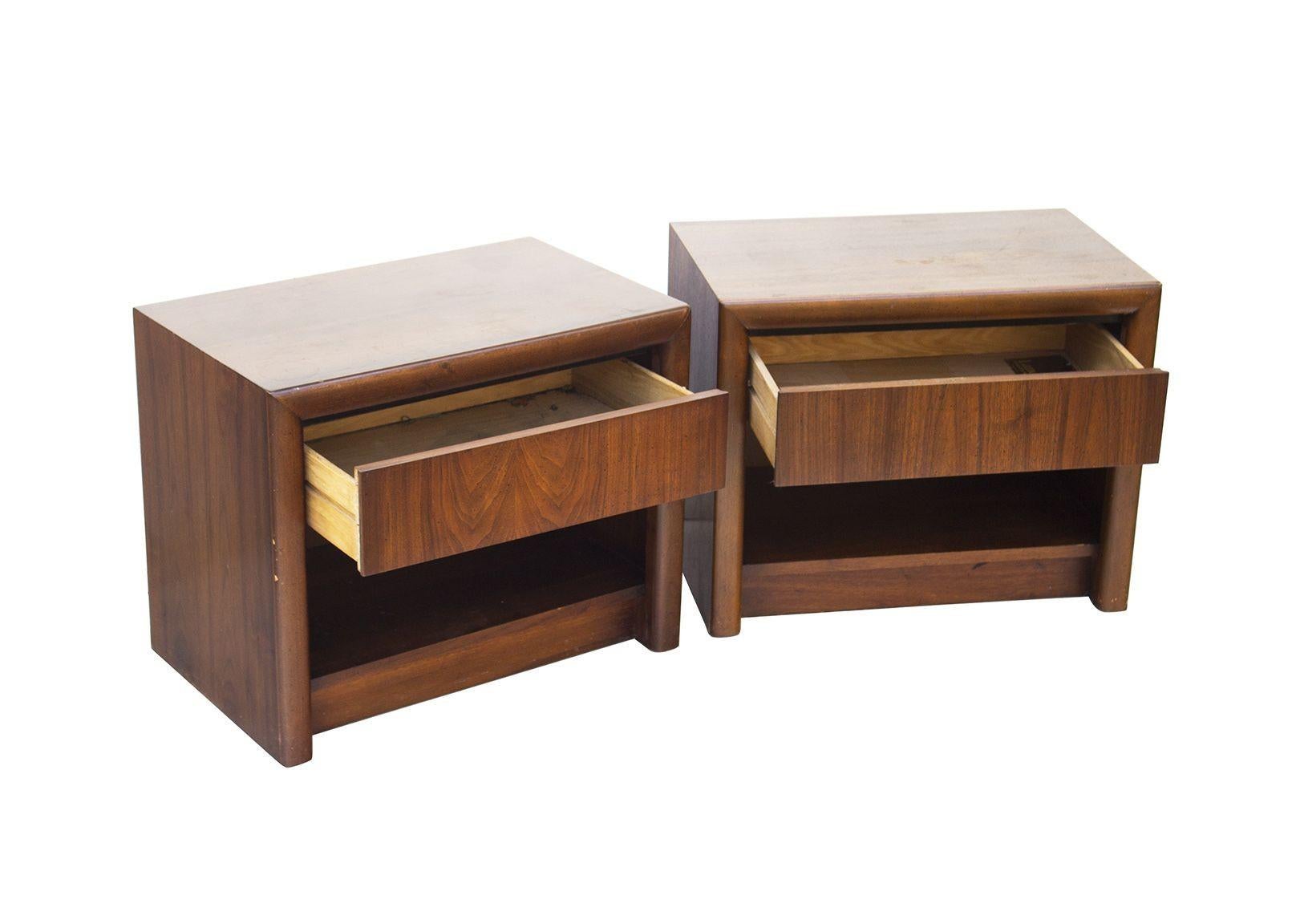 USA, 1970s
Pair of Mid-Century Modern walnut nightstands made by Lane Furniture. Each has a single drawer for concealed storage coupled with an open shelf below. Substantial, well-made pieces in rich, warm American black walnut. 
CONDITION NOTES: