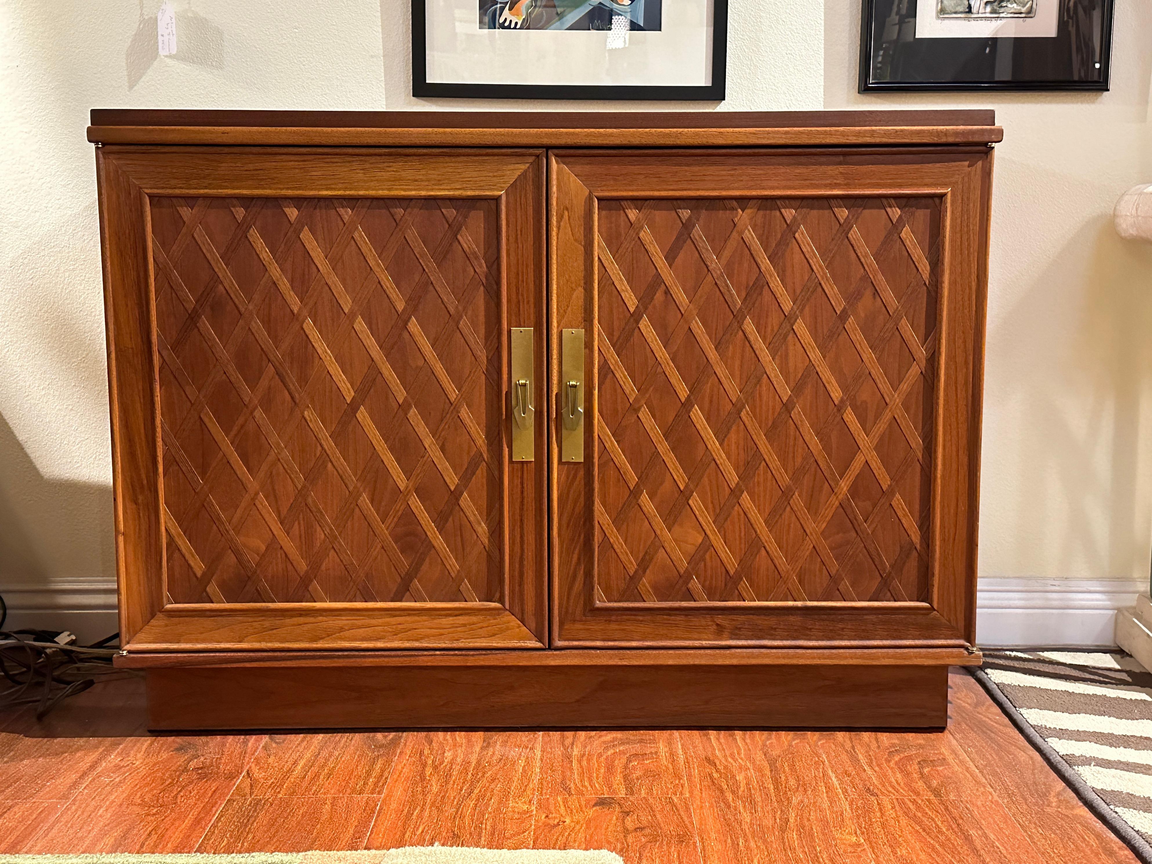 Dating back to the 1960s, this Midcentury Walnut Storage Cabinet by Brown Saltman encapsulates the essence of classic mid-century aesthetics.

Crafted from walnut, this piece boasts a sophisticated diamond pattern.The cabinet's facade is adorned