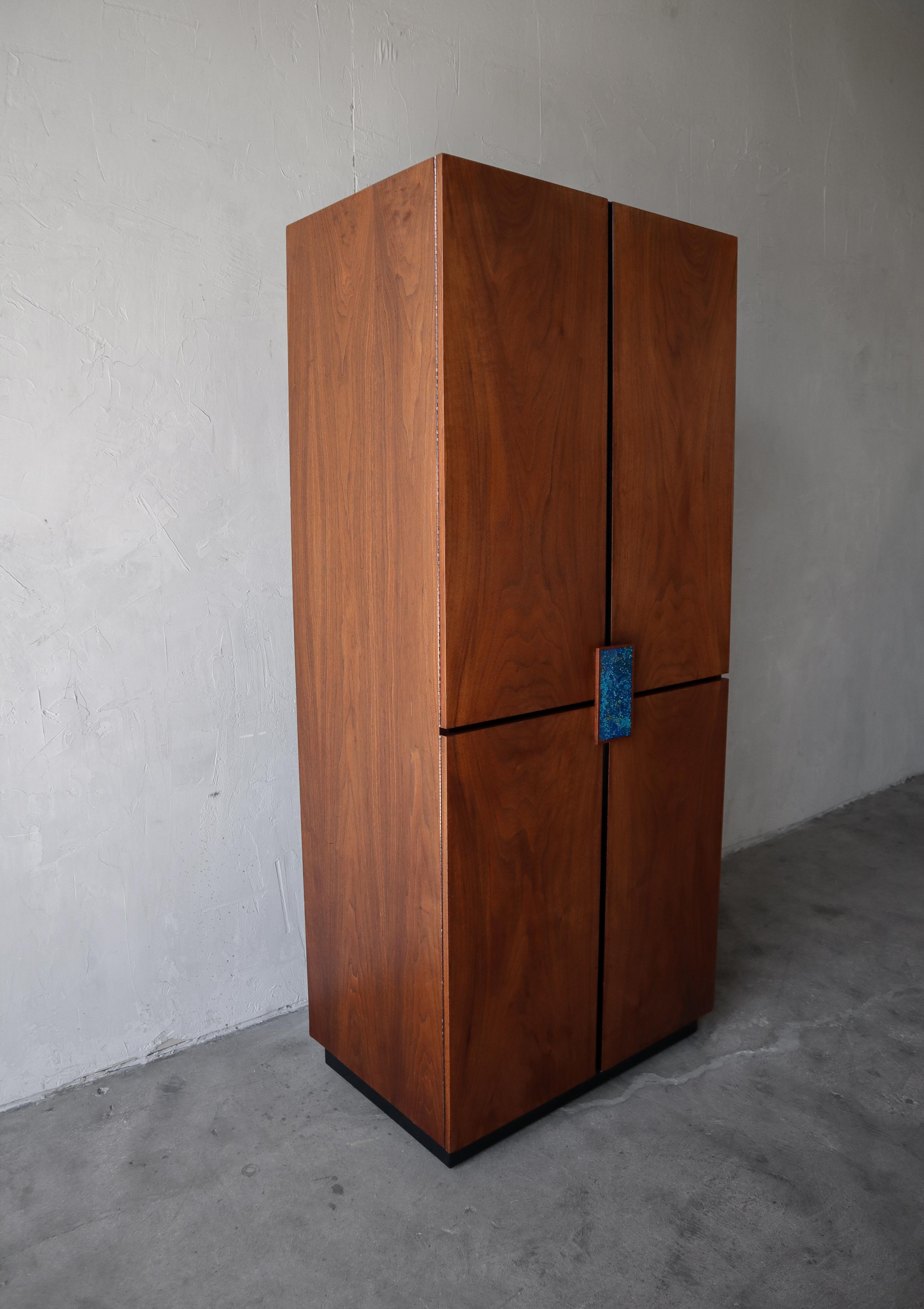 Magnifique armoire en noyer du milieu du siècle, réalisée par Richard Thompson pour Glenn of California. L'armoire est en noyer magnifiquement grainé avec des détails noirs. L'armoire comporte également une magnifique poignée en émail