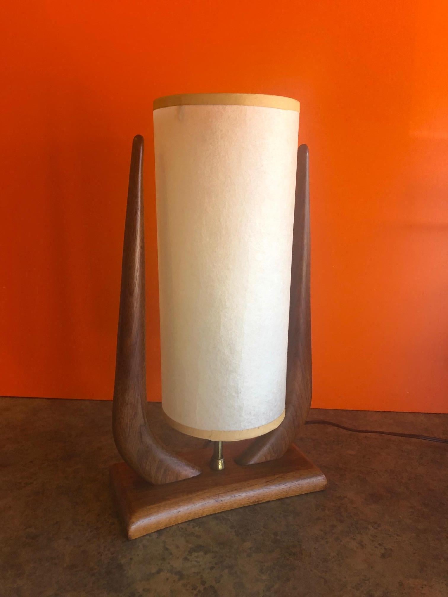 Midcentury walnut table lamp by Modeline Lamp Co., circa 1960s. 

Lamp base is in very good vintage condition; original shade is in good condition with no holds or cracks and measures 12