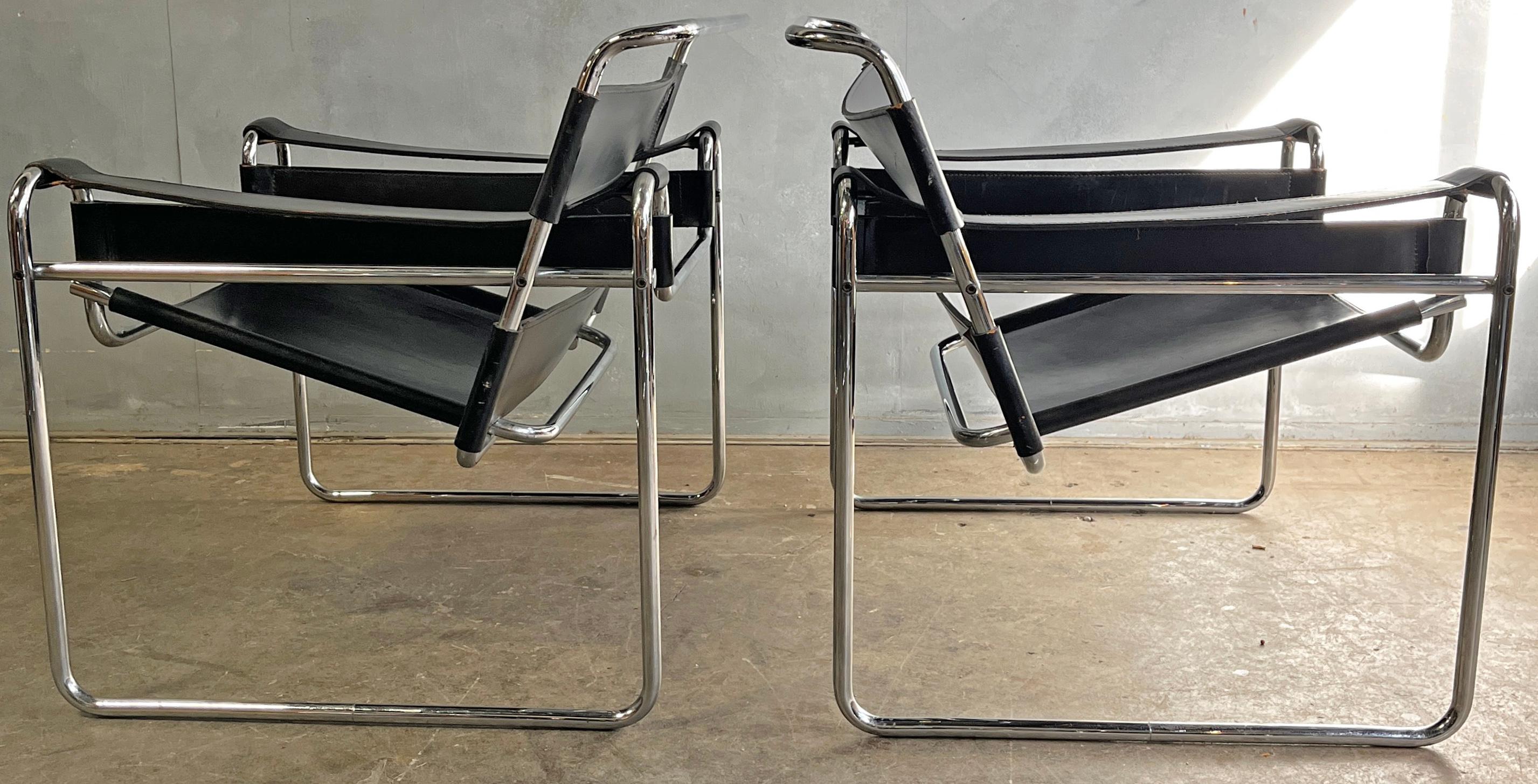 Wassily lounge chairs designed by Marcel Breuer in black full leather. This vintage pair has unique traits for authenticity verification such as flat caps on the end tubes, black hex screws, and thick cowhide leather. Bought together with the B33
