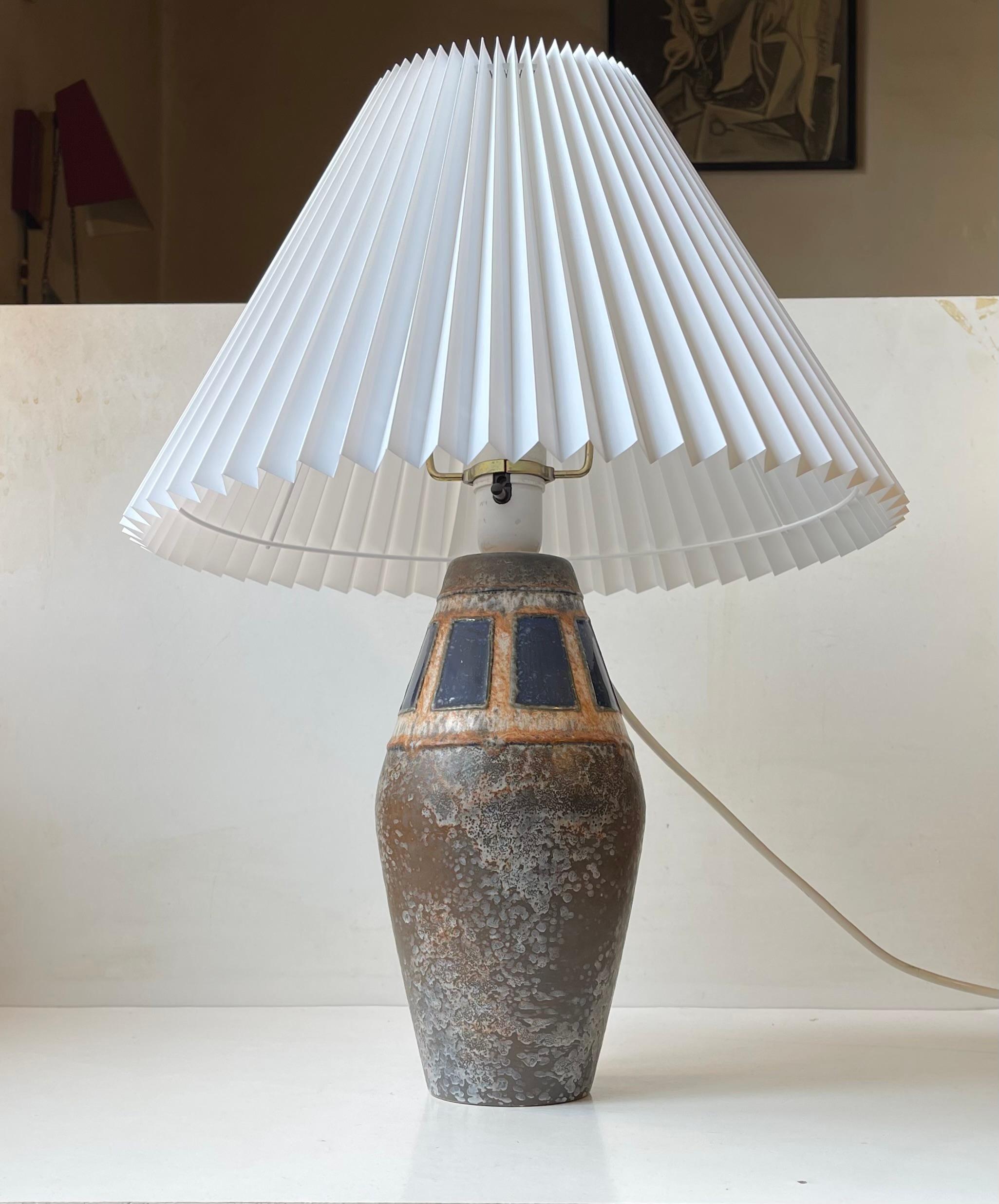 Large pottery table lamp decorated with spotted earthy ash glazes and blue squares. Marked Western Germany 27 beneath its base. It comes with a new white fluted Danish shade with a diameter of 38 cm. The total height of the lamp is 50 cm (can be