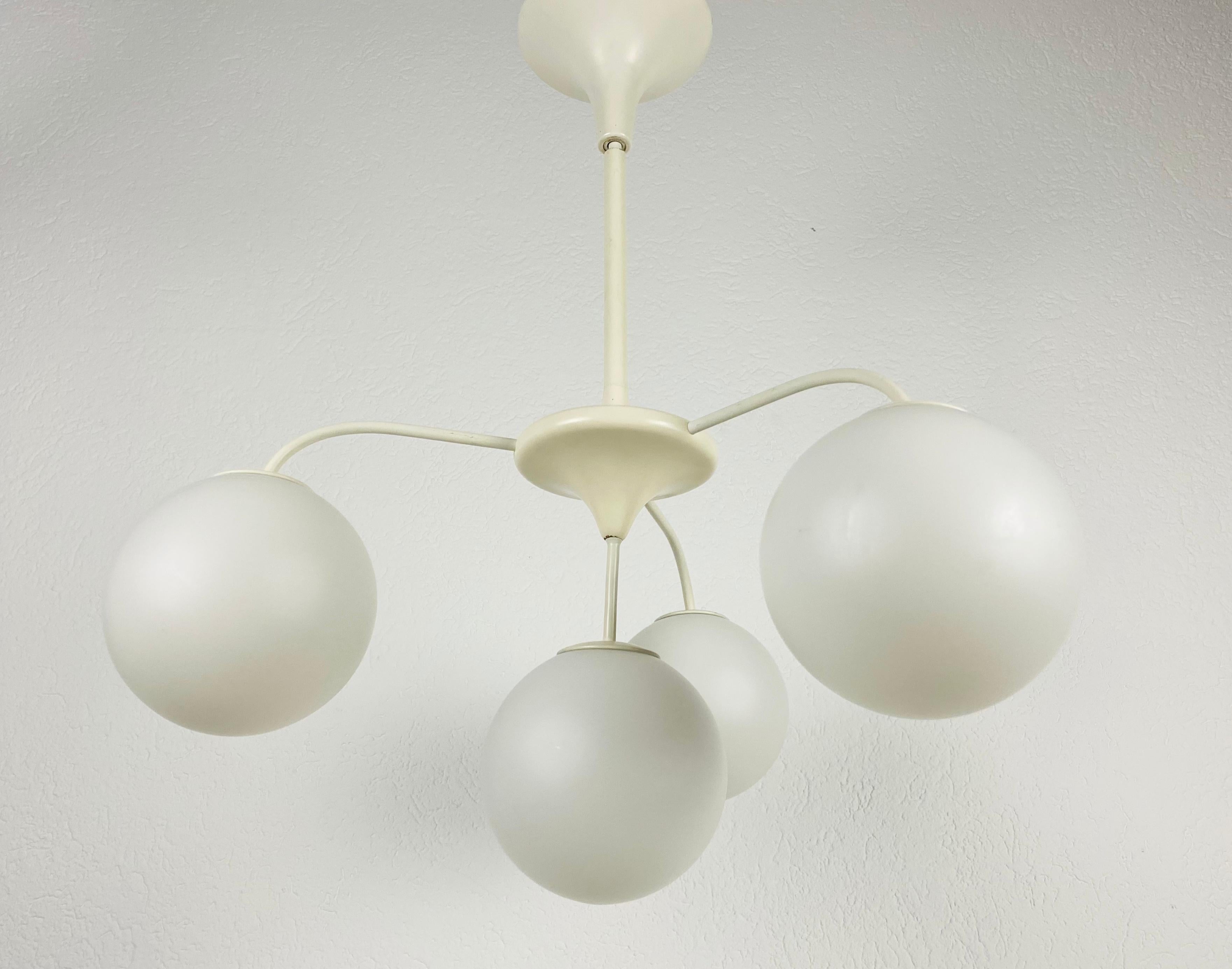 A midcentury chandelier by Max Bill for Temde made in Switzerland in the 1960s. It is fascinating with its Space Age design and four opaque balls. The white circular body of the light is made of full metal, including the arms. White bar with white