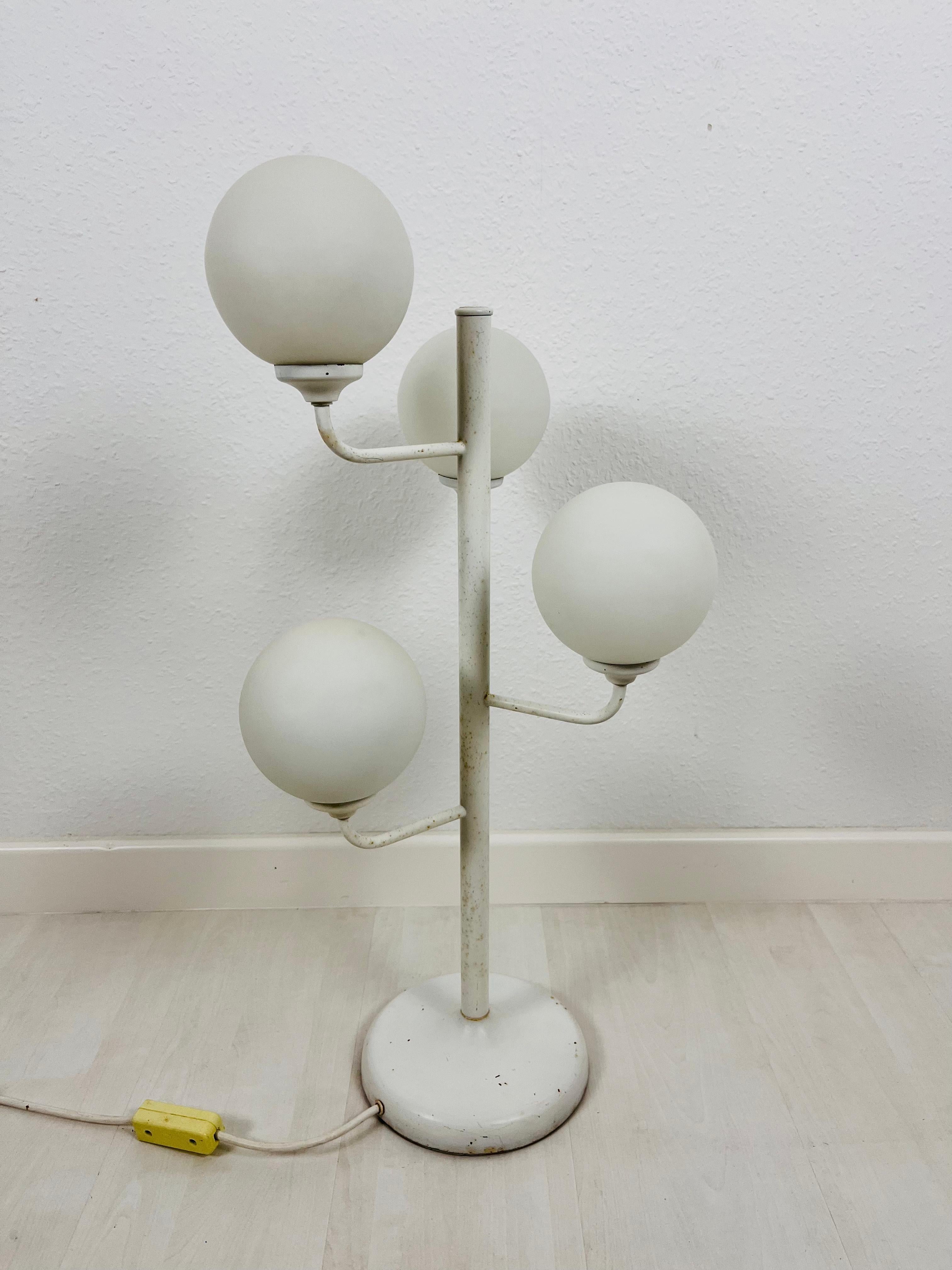 A midcentury floor lamp made in Germany in the 1960s. It is fascinating with its Space Age design and four ball shaped opaque balls. The bottom of the light is made of full metal. The bar is also made of metal including the arms.

Very good vintage