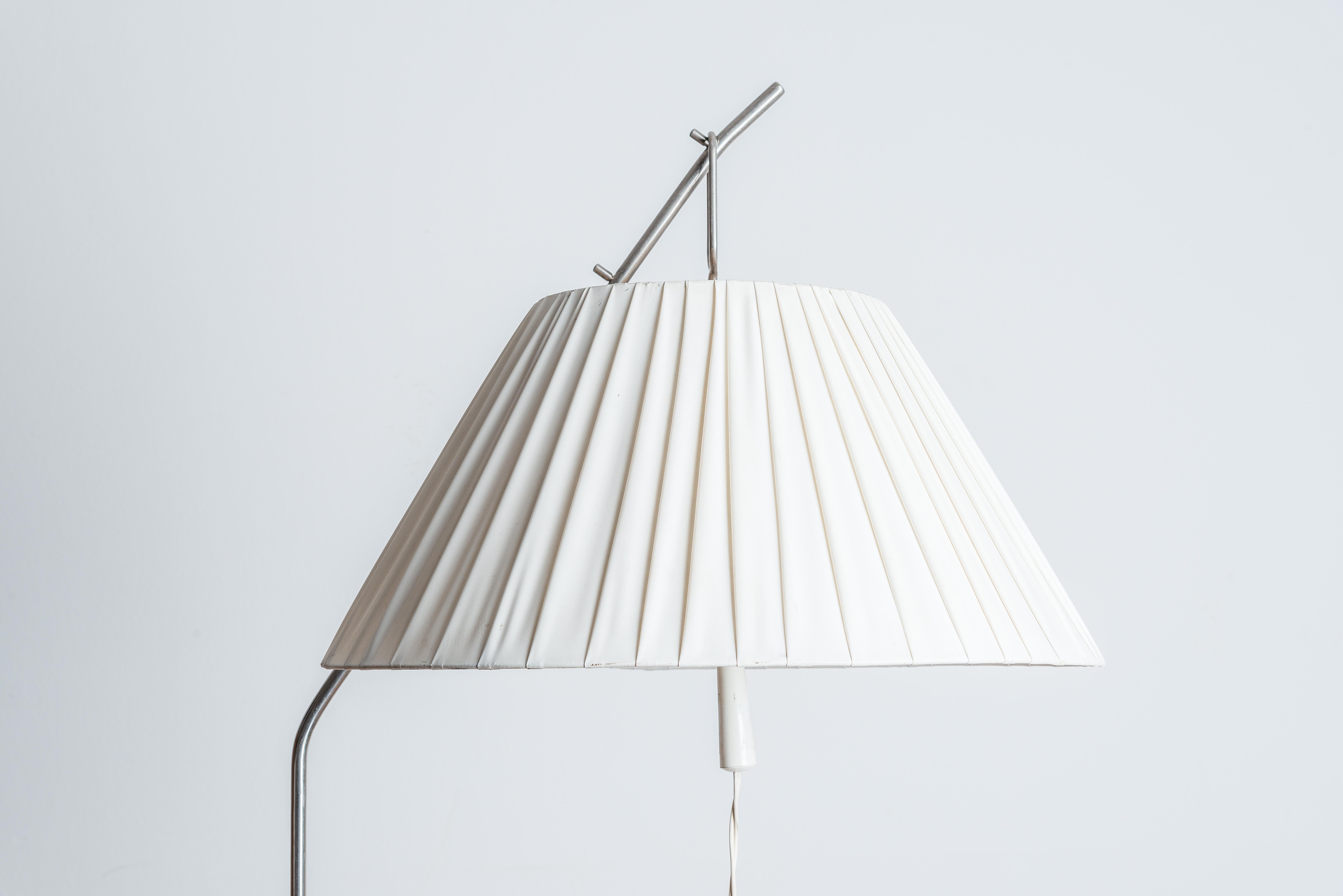 Midcentury white Kalmar-style floor lamp with . Pleated Vinyl Lamp Shade.Country of origin: Poland, made in the 1960s
The shade can be adjusted to 3 different heights using a clever solution of 3 different hooks on the top. 
Excellent design