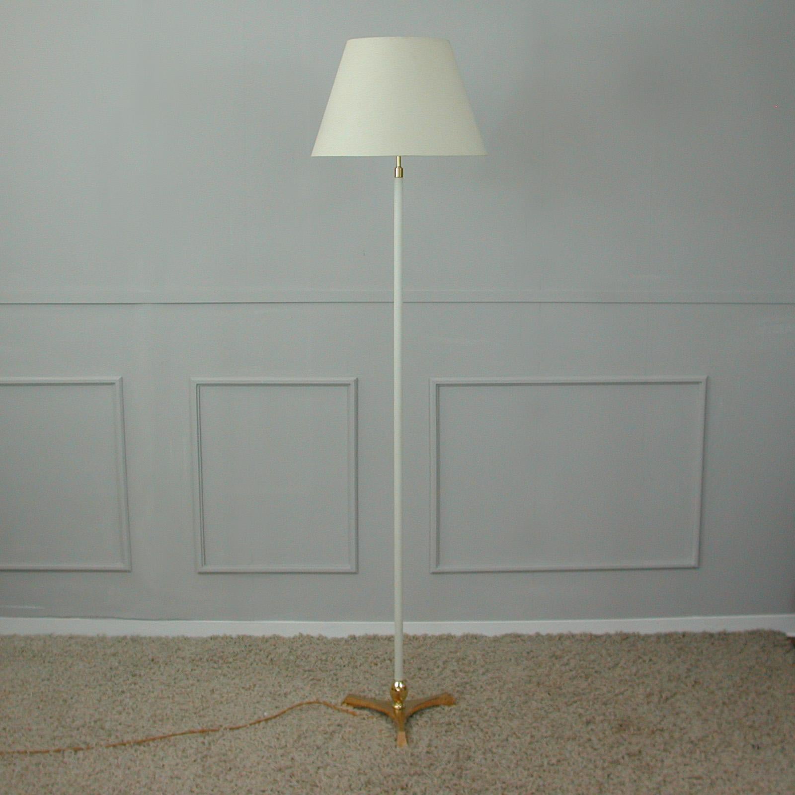 This unusual midcentury floor lamp was designed and manufactured in Germany in the 1950s to 1960s. It features a brass tripod base and saddle-stitched off white leather rod.

The lamp has got 2 E27 sockets for bulbs up to 60 Watt each. Wired for