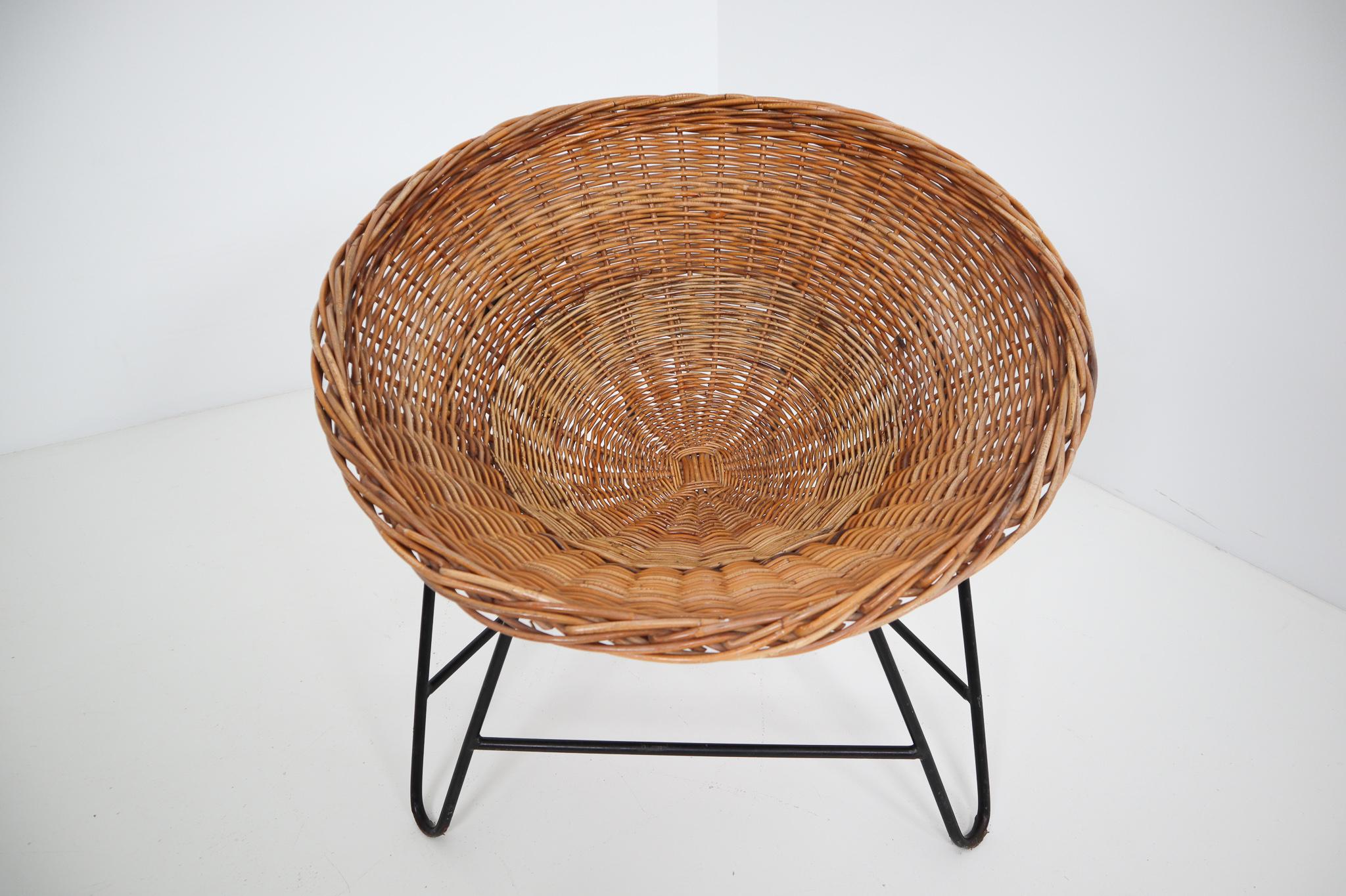 Wicker midcentury easy chairs designed and produced in Europe during the 1960s. The chairs are made from handwoven wicker for the seat that is formed into a basket. The frame is made of black lacquered steel. They are comfortable to sit in and