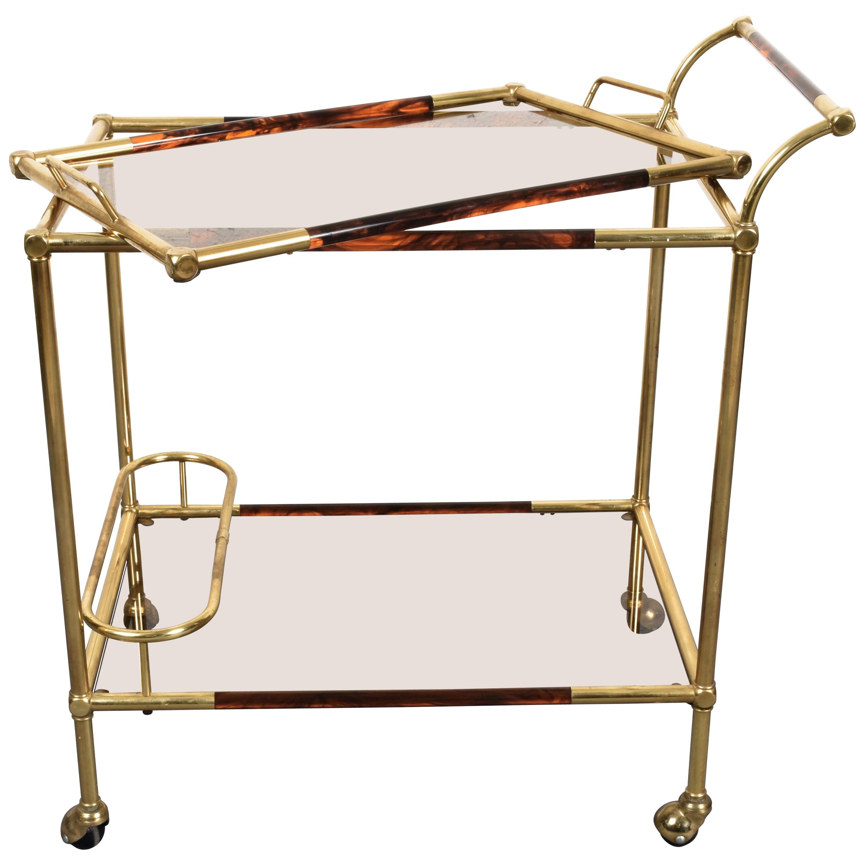 Elegant golden brass and Lucite tortoiseshell trolley. This item is attributed to Willy Rizzo and was produced in Italy during 1980s.

This item is very ductile as its top may be used as a wonderful service tray when needed. The bottom shelf has a