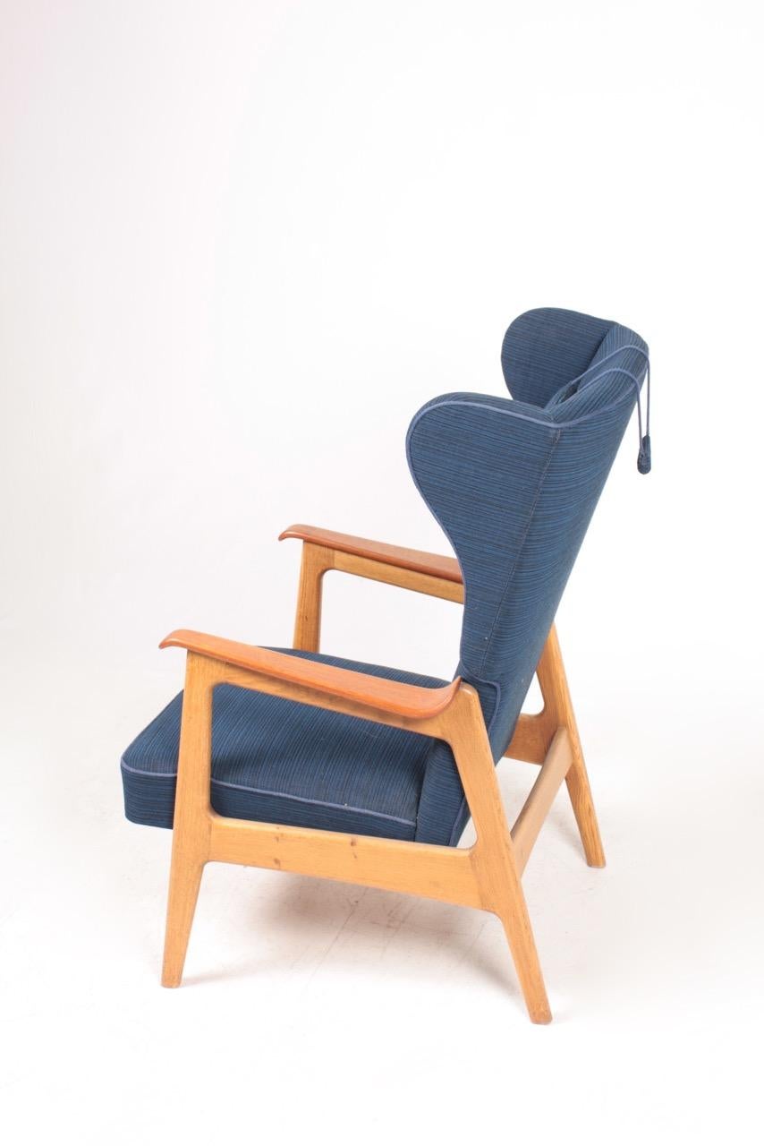 Great looking wingback chair in teak, oak and original fabric. Designed and made in Denmark in the 1960s.