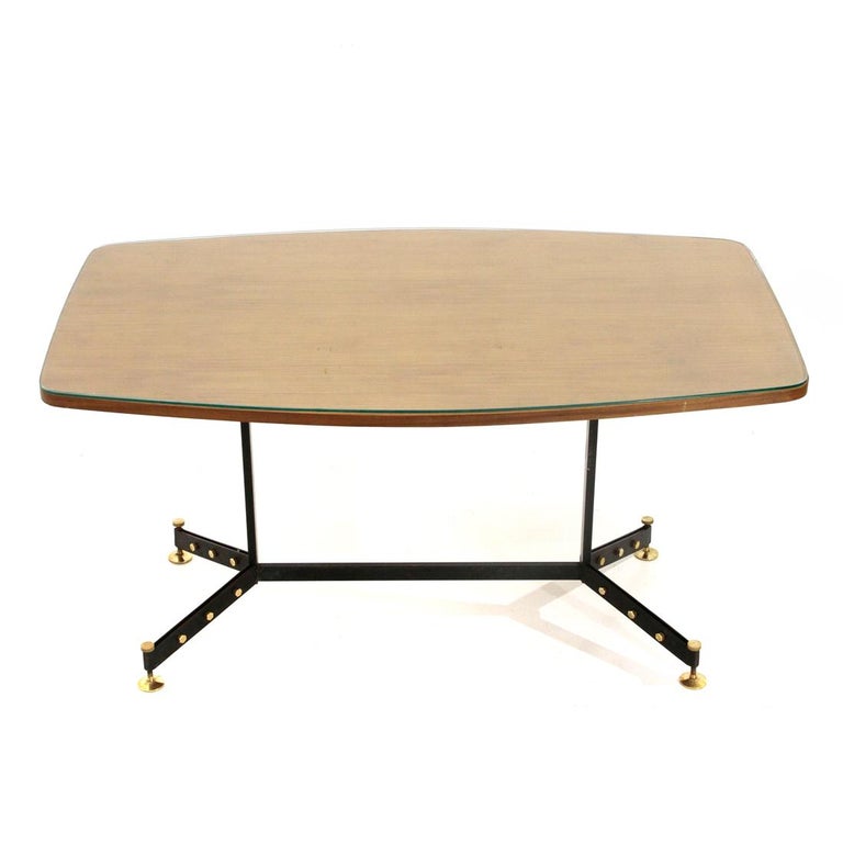 Italian-made dining table produced in the 1950s.
Rectangular top with convex long sides and rounded corners in veneered wood and transparent glass.
Structure in black painted metal with brass studs.
Height adjustable feet in brass.
Good general