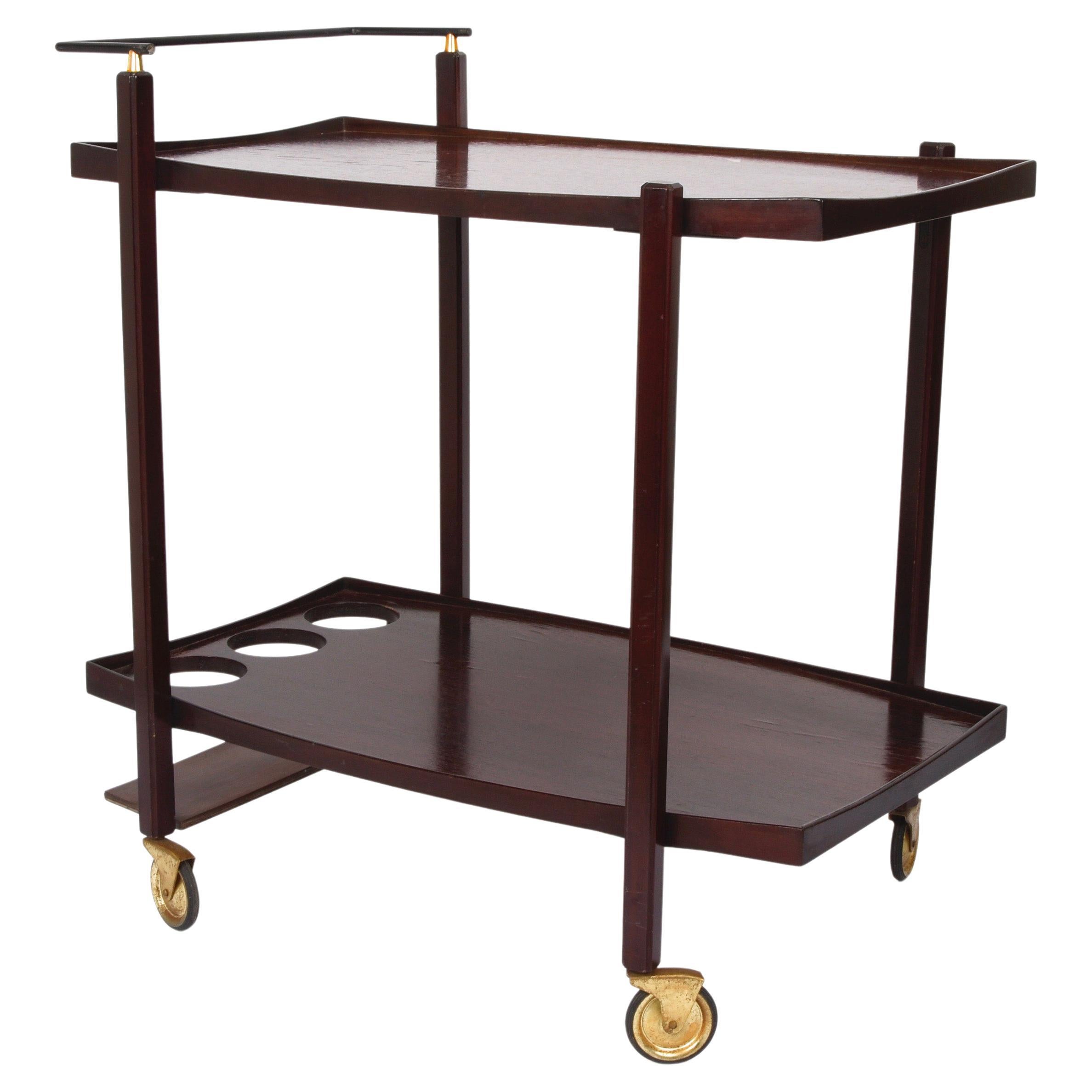 Amazing midcentury wood serving bar cart with enamelled metal bottle holder. This fantastic item was designed in Italy during the 1960s.

This modern mid-century serving cart is made of two dark brown teakwood floors, one of which has a bottle