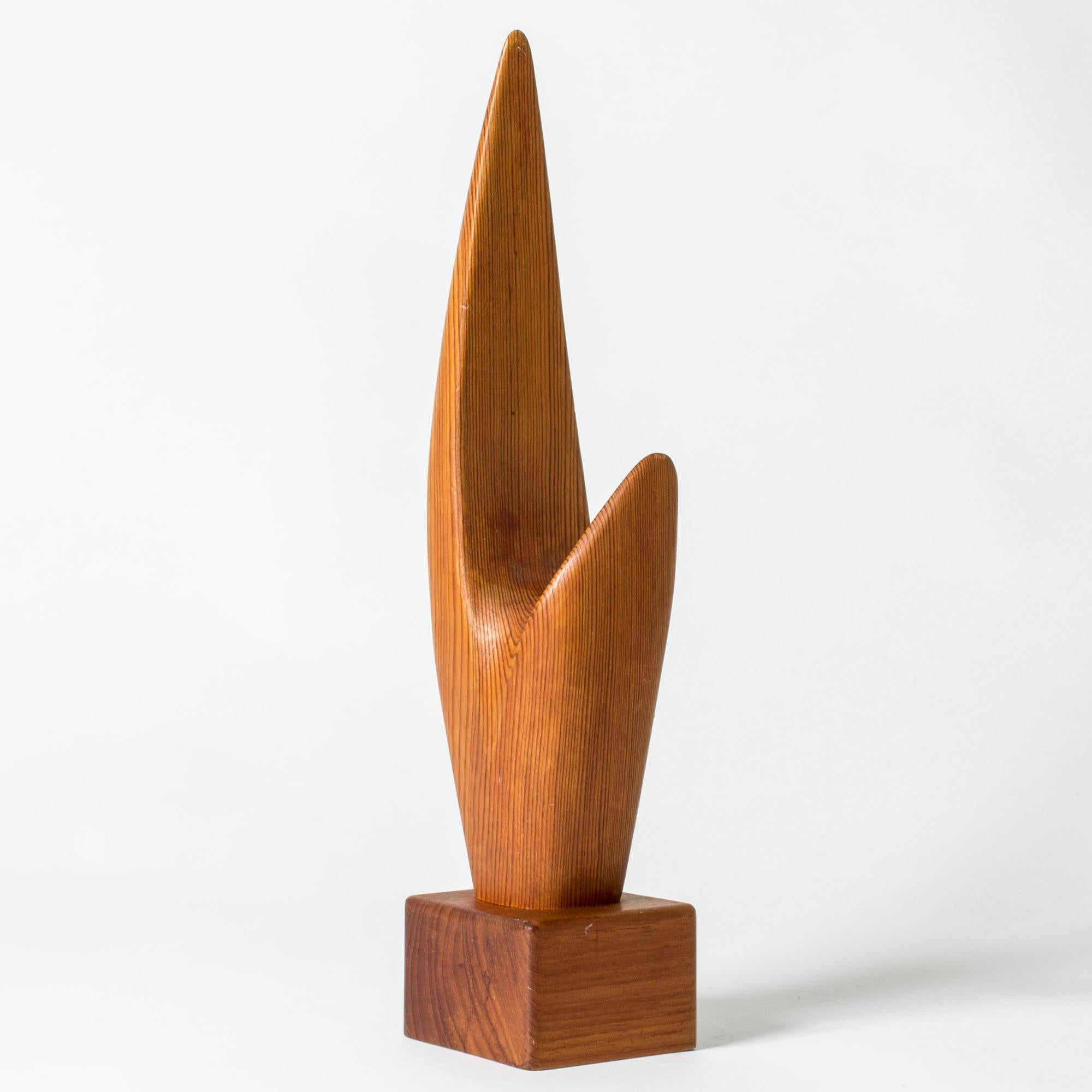 Auffällige Holzskulptur in abstrakter Form von Johnny Mattsson. Kiefer auf einem Sockel aus Teakholz. Die Form der Skulptur folgt in schöner Weise der Maserung des Kiefernholzes.