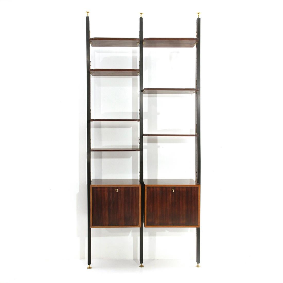 Italian manufacture bookcase produced in the 1950s
Uprights in black painted wood with brass terminals adjustable in height.
Storage compartments and shelves in veneered wood.
Shelves with tapered edge.
Storage compartments with flap opening,
