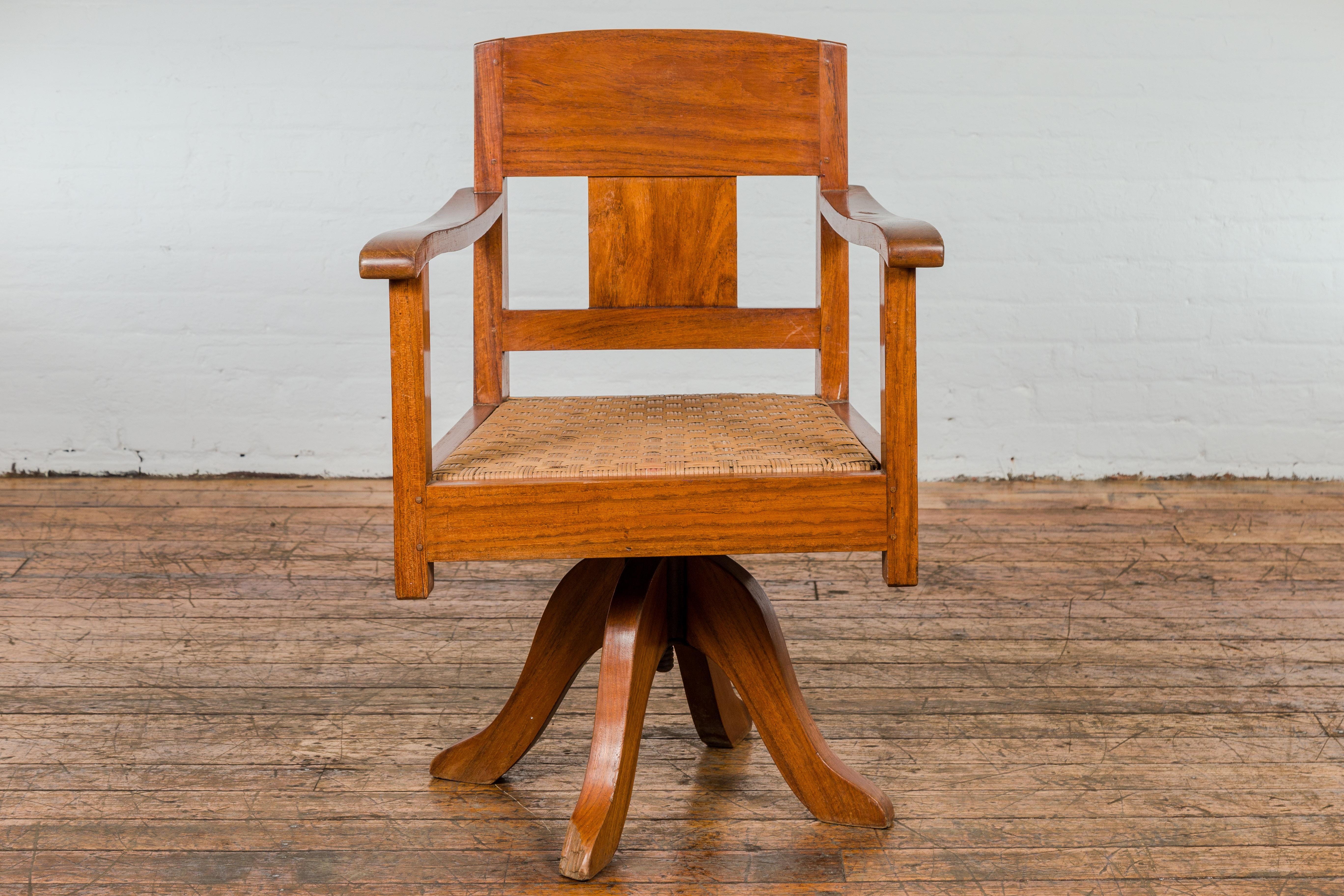 Ein Holzdrehstuhl aus der Mitte des Jahrhunderts mit geflochtenem Rattansitz und Vierfußgestell. Tauchen Sie ein in den Charme der Midcentury-Ära mit diesem exquisiten Holzdrehstuhl, einer perfekten Mischung aus Form und Funktion. Der Stuhl zeichnet