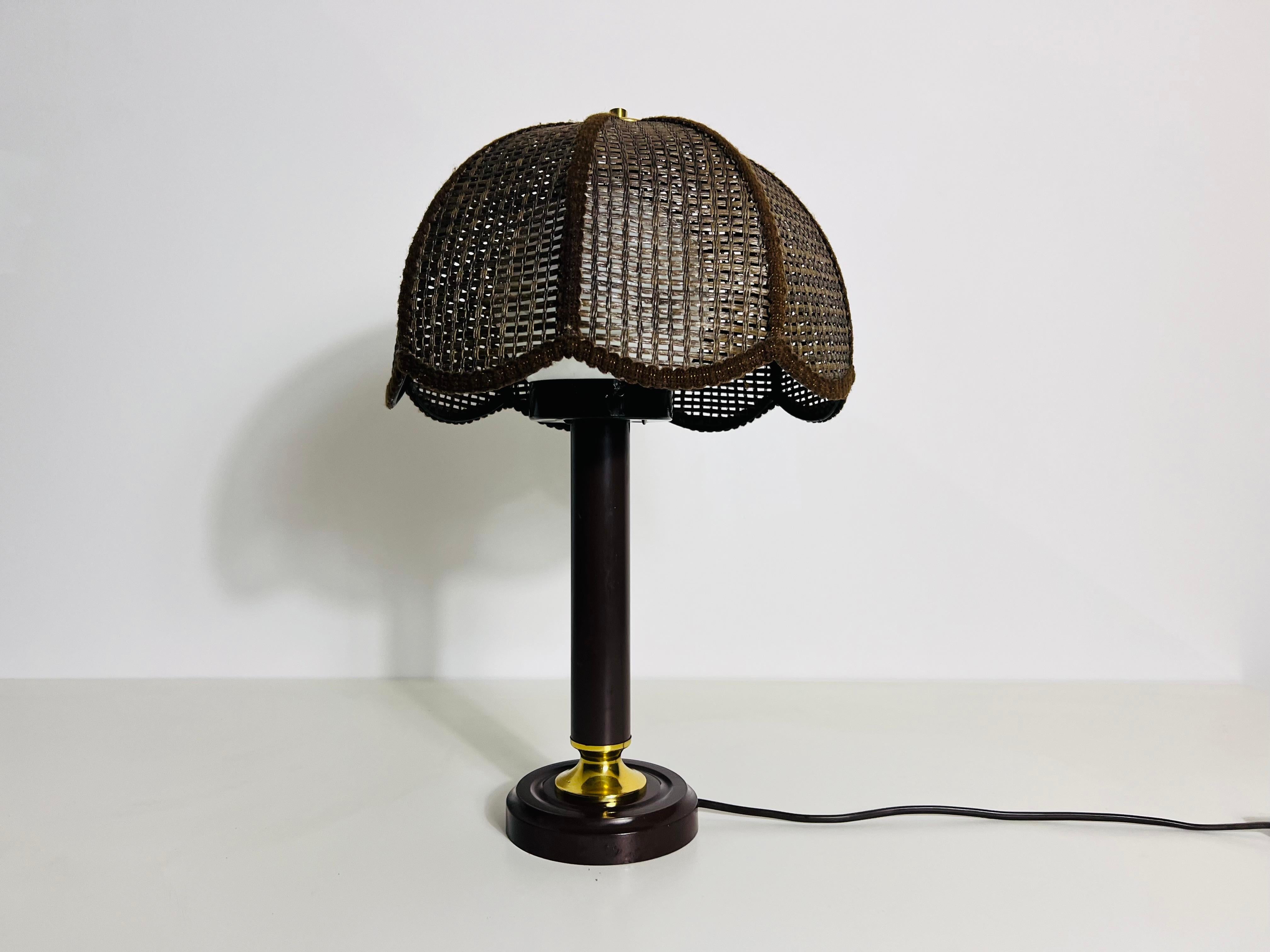 Cette lampe de table, fabriquée en bois de bambou foncé, présente un design où le bois s'ouvre vers le haut. Au sommet, un globe rond en verre opale est maintenu sur le support en bois. La lampe affiche un design très naturel, utilisant des