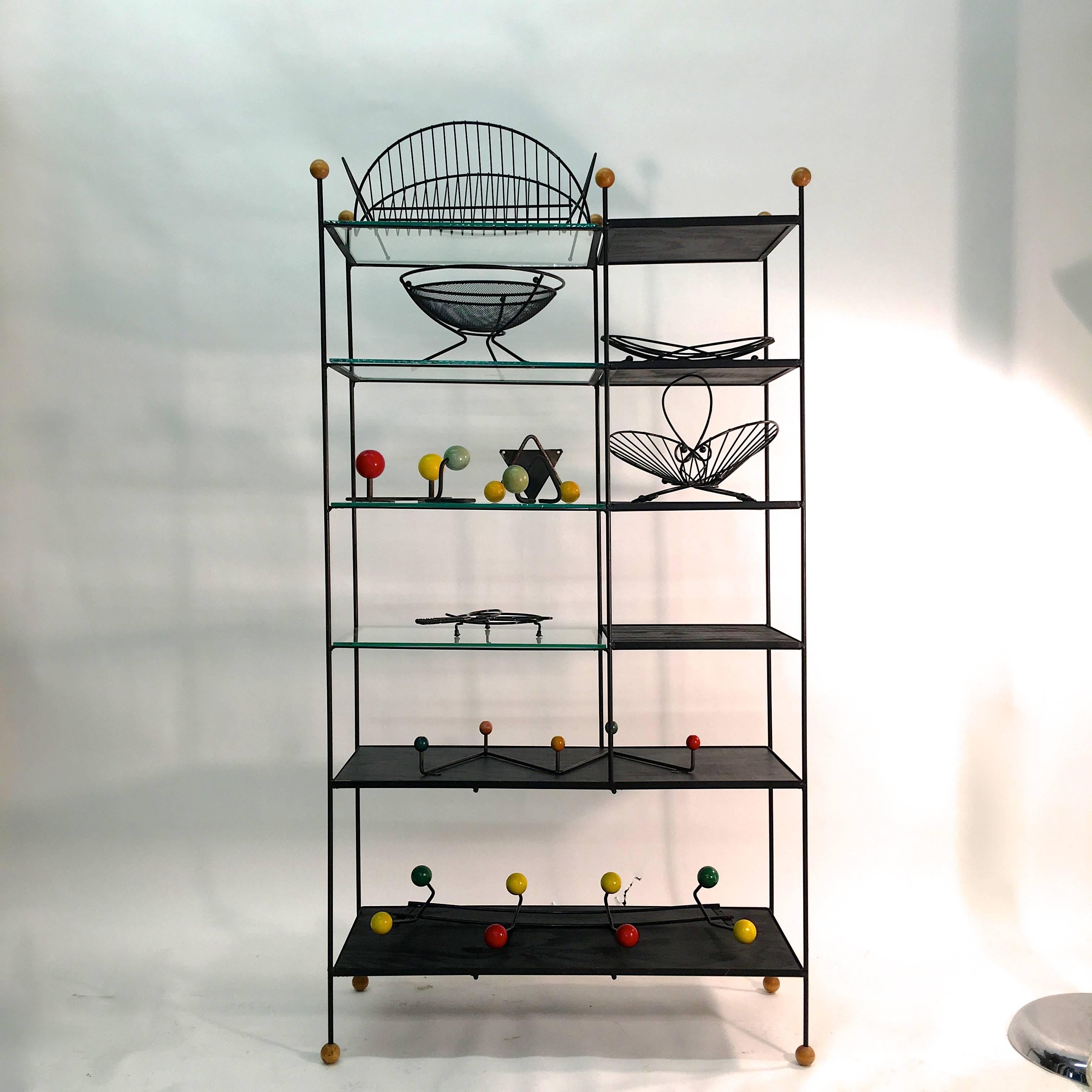 PLEASE NOTE THIS IS ONE ETAGERE. NOT “a set”. PRICE SHOWN IS FOR THE ONE. 

A single mid-century modern blackened iron framed étagère with inset painted wood and glass shelves and wood balls for feet and finials. This came out of the post-war modern