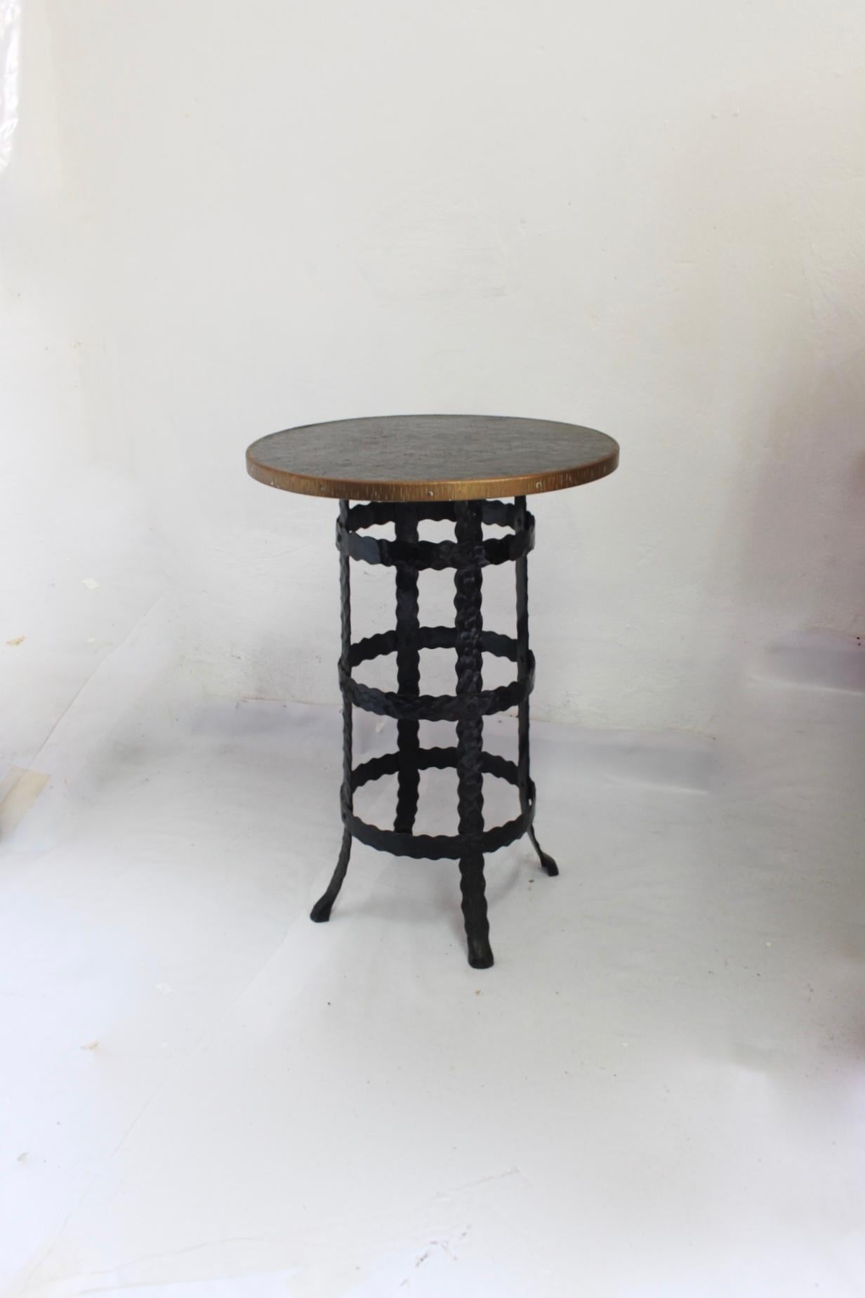 Midcentury wrought iron and wood round coffee or side high table, 1950s the piece features black wood and an embossed metal top, a brass outer ring, and legs finishing in lion paw shapes.
