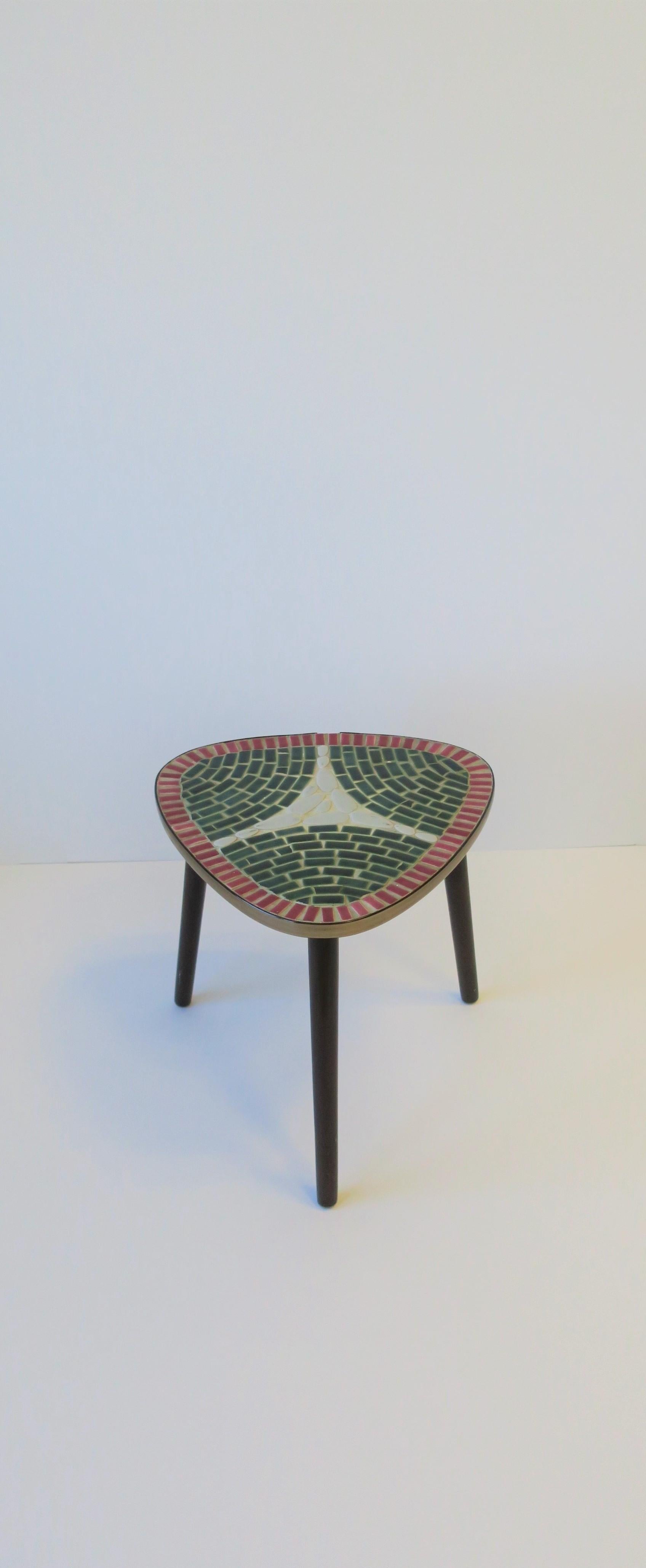 A very beautiful, small and low, Mid-Century Modern period tile mosaic side table with tripod wood base, circa mid-20th century, 1960s, Japan. Mosaic tile colors include: raspberry red, forest green, and a light grey. Table is great for drinks, as a