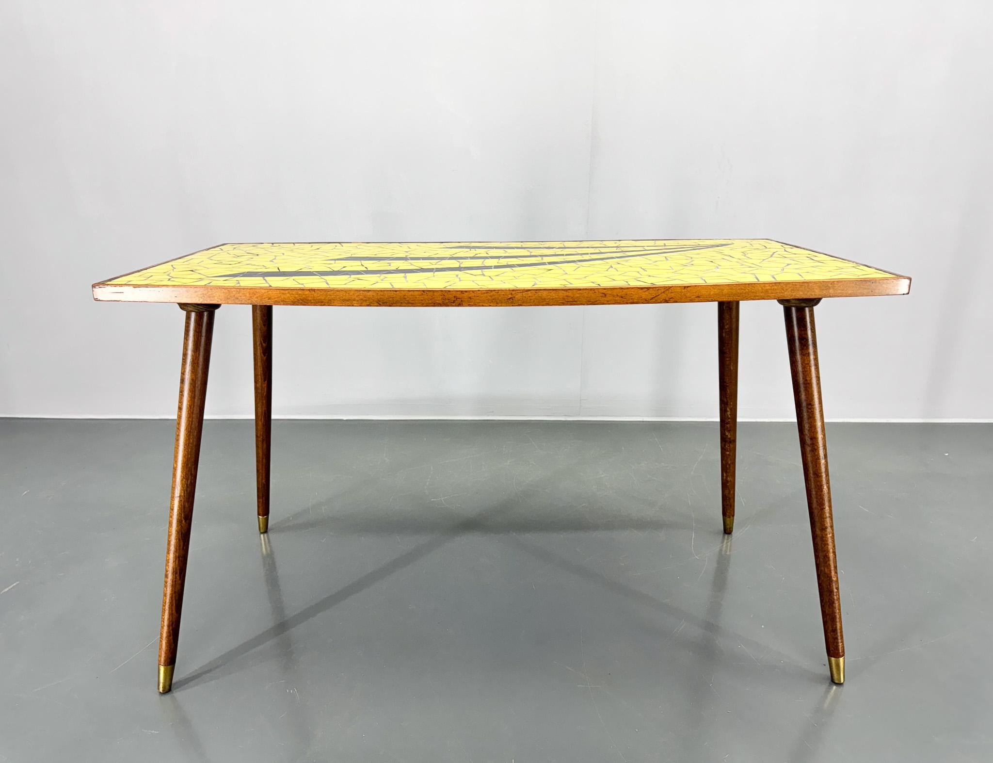 Table d'appoint ou table basse vintage fabriquée en Allemagne dans les années 70. Le dessus est incrusté de mosaïque de verre coloré. Les pieds de la table sont munis de ferrures en laiton à la base.