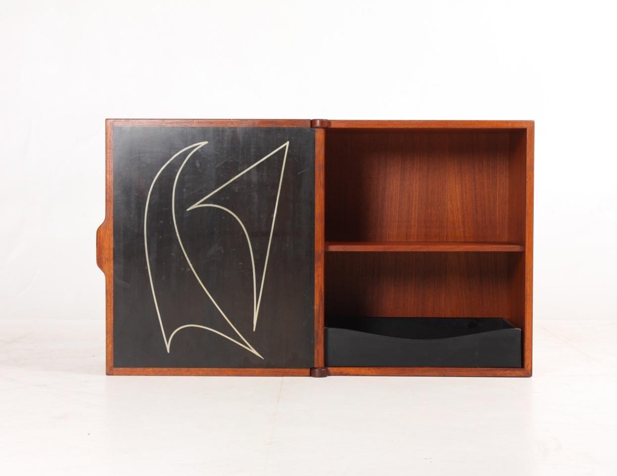 Wall-mounted cabinet in teak. Designed and made in the 1950s. Great original condition.